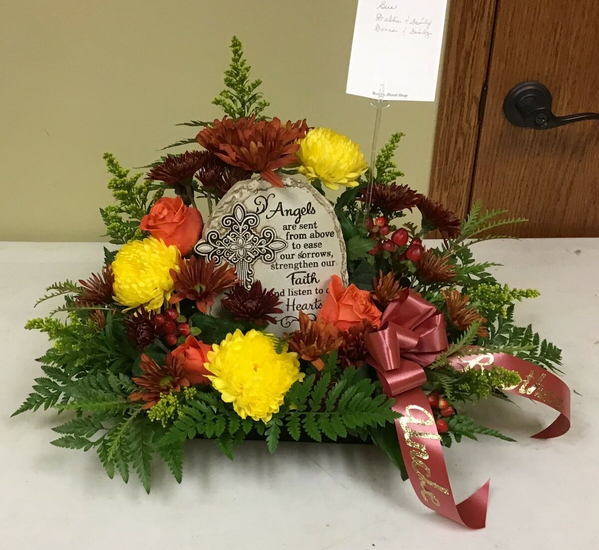 A wreath of flowers with a plaque that says angels