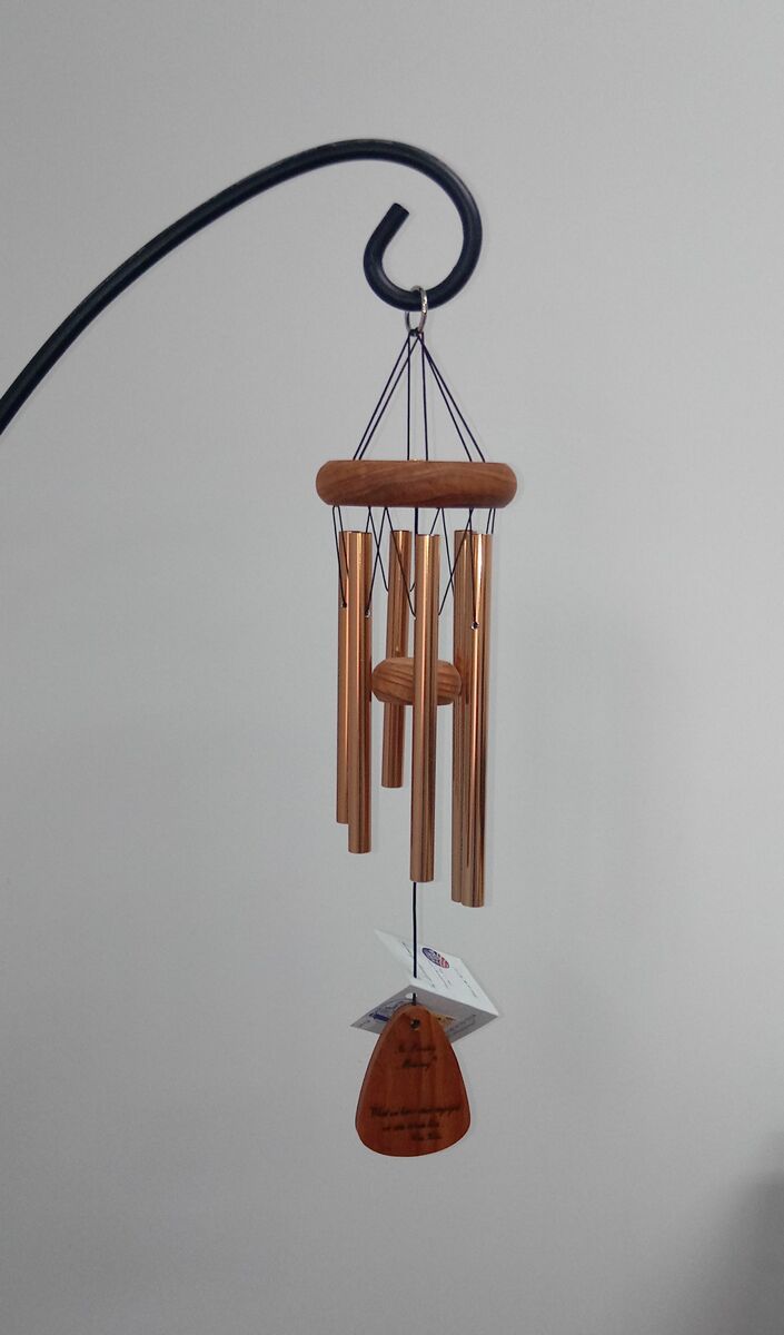 A wind chime is hanging from a metal hook