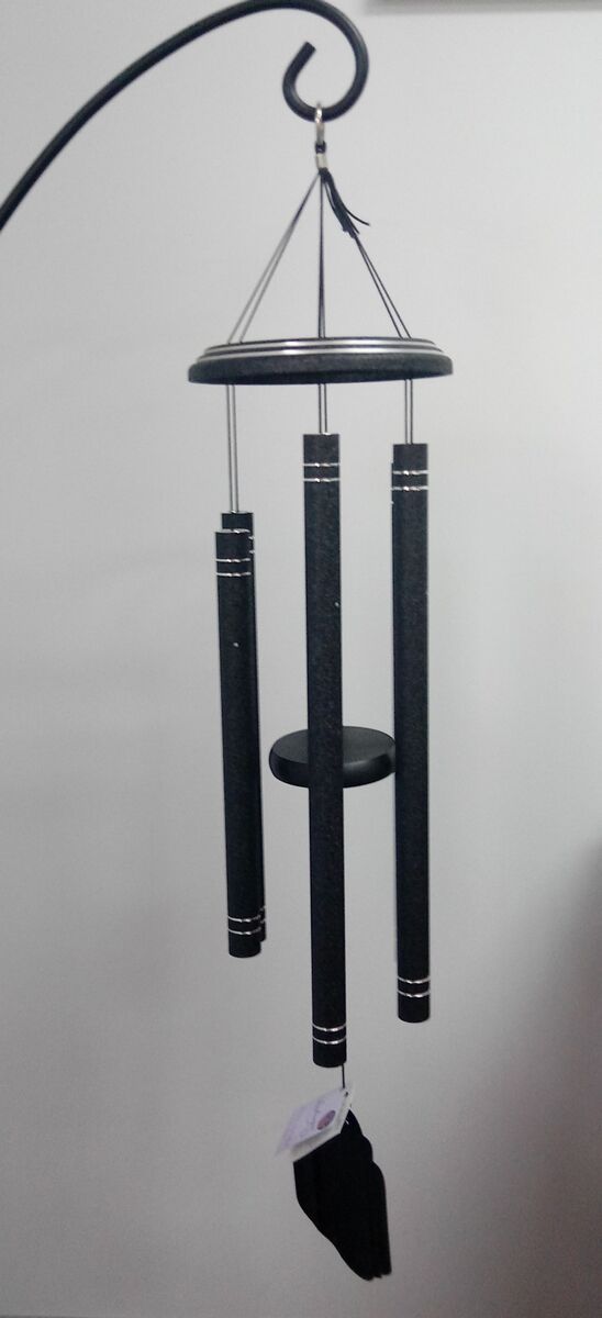 A black wind chime is hanging from a metal pole.