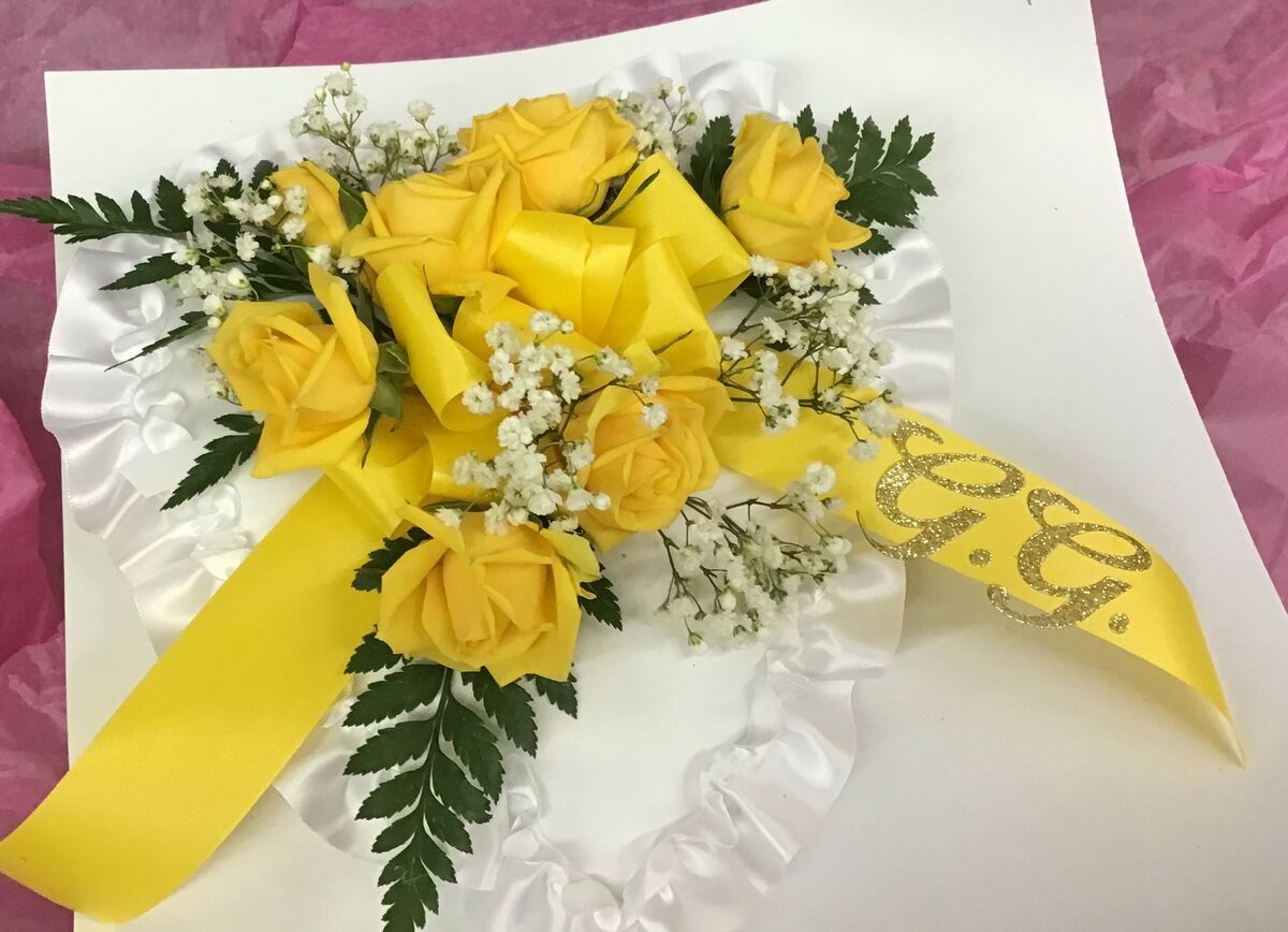 A white pillow with yellow roses and baby 's breath on it