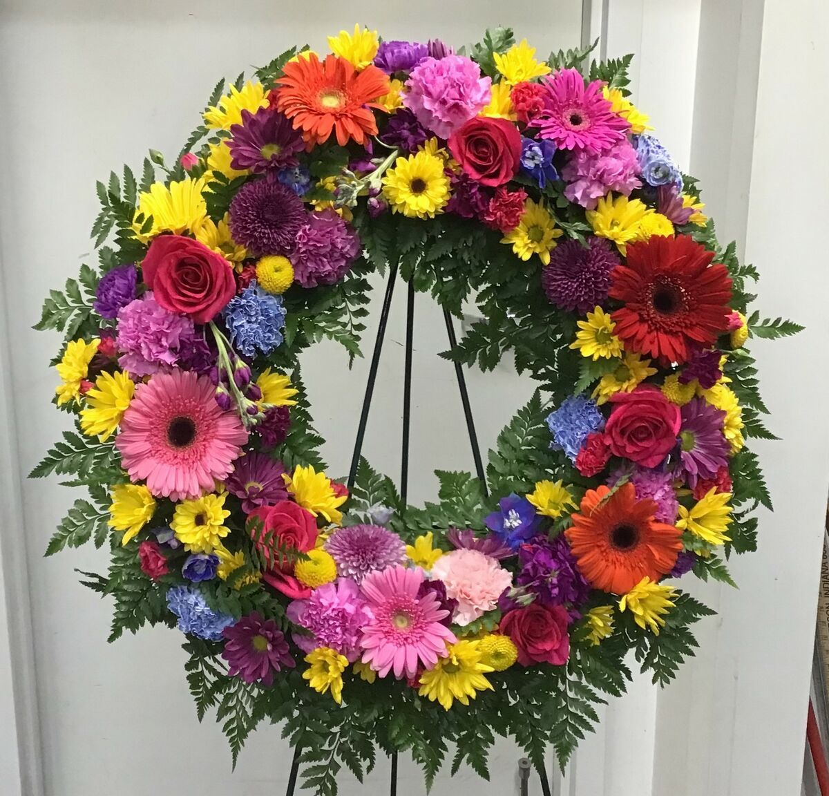 A wreath of colorful flowers is sitting on a stand