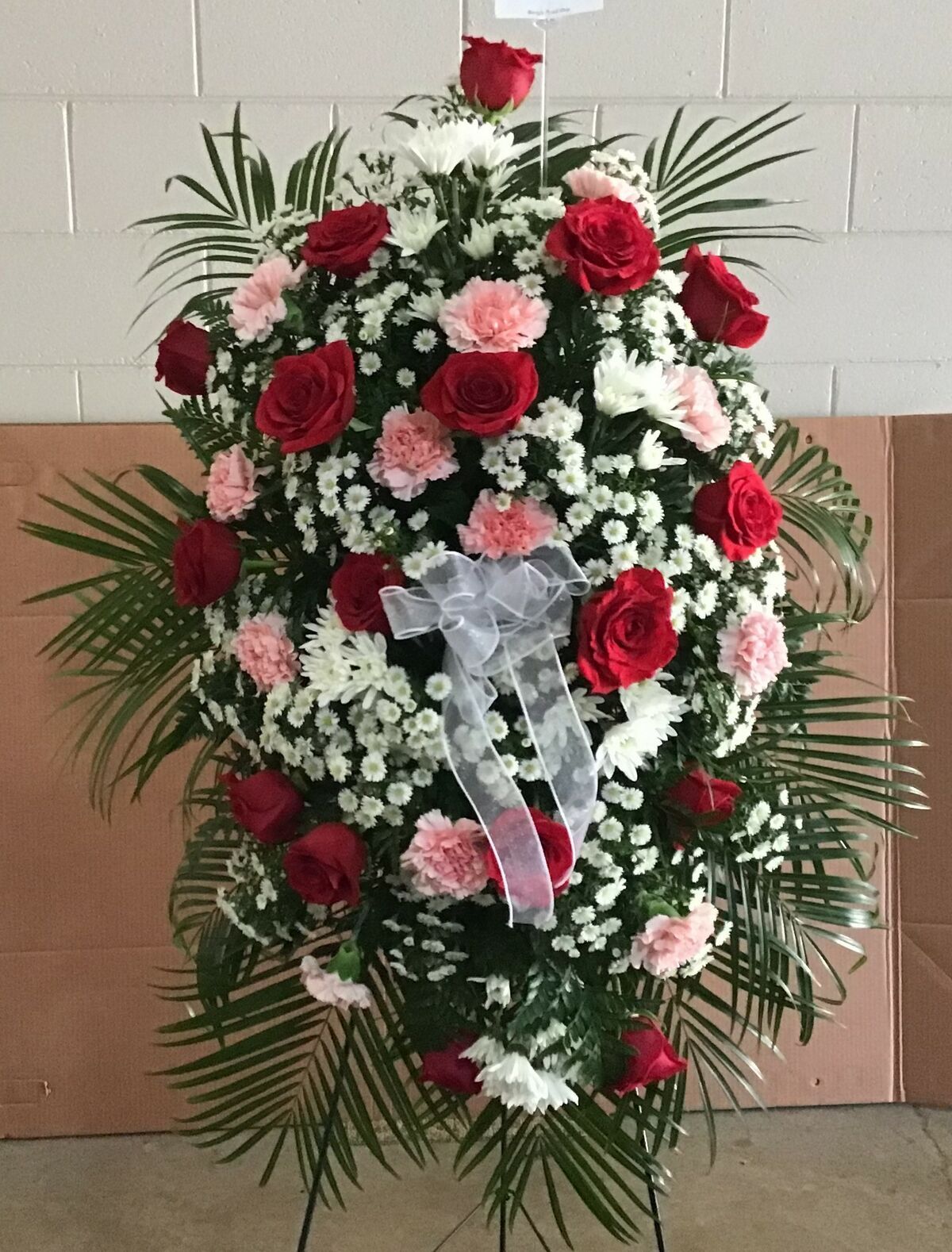A wreath with red roses , pink carnations and baby 's breath