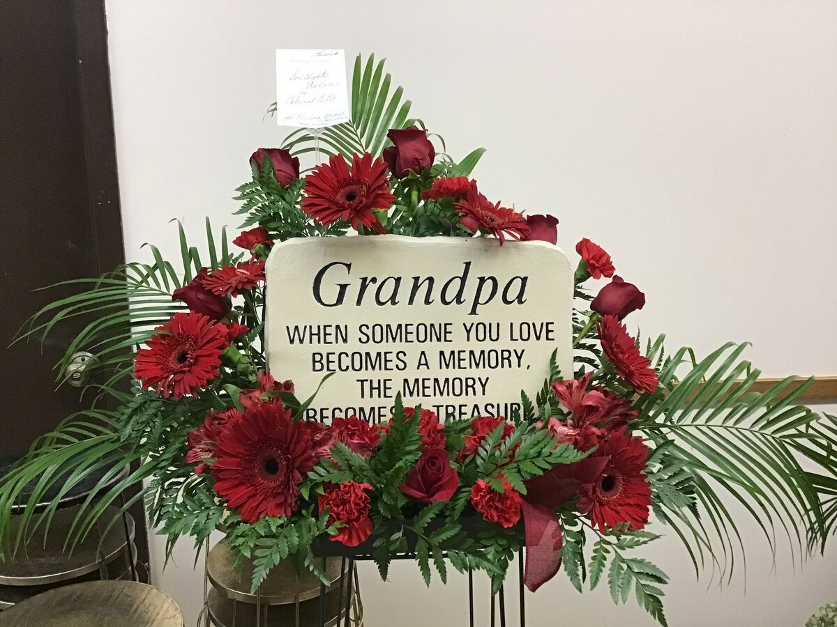 A bouquet of red flowers with a sign that says `` grandpa when someone you love becomes a memory . ''