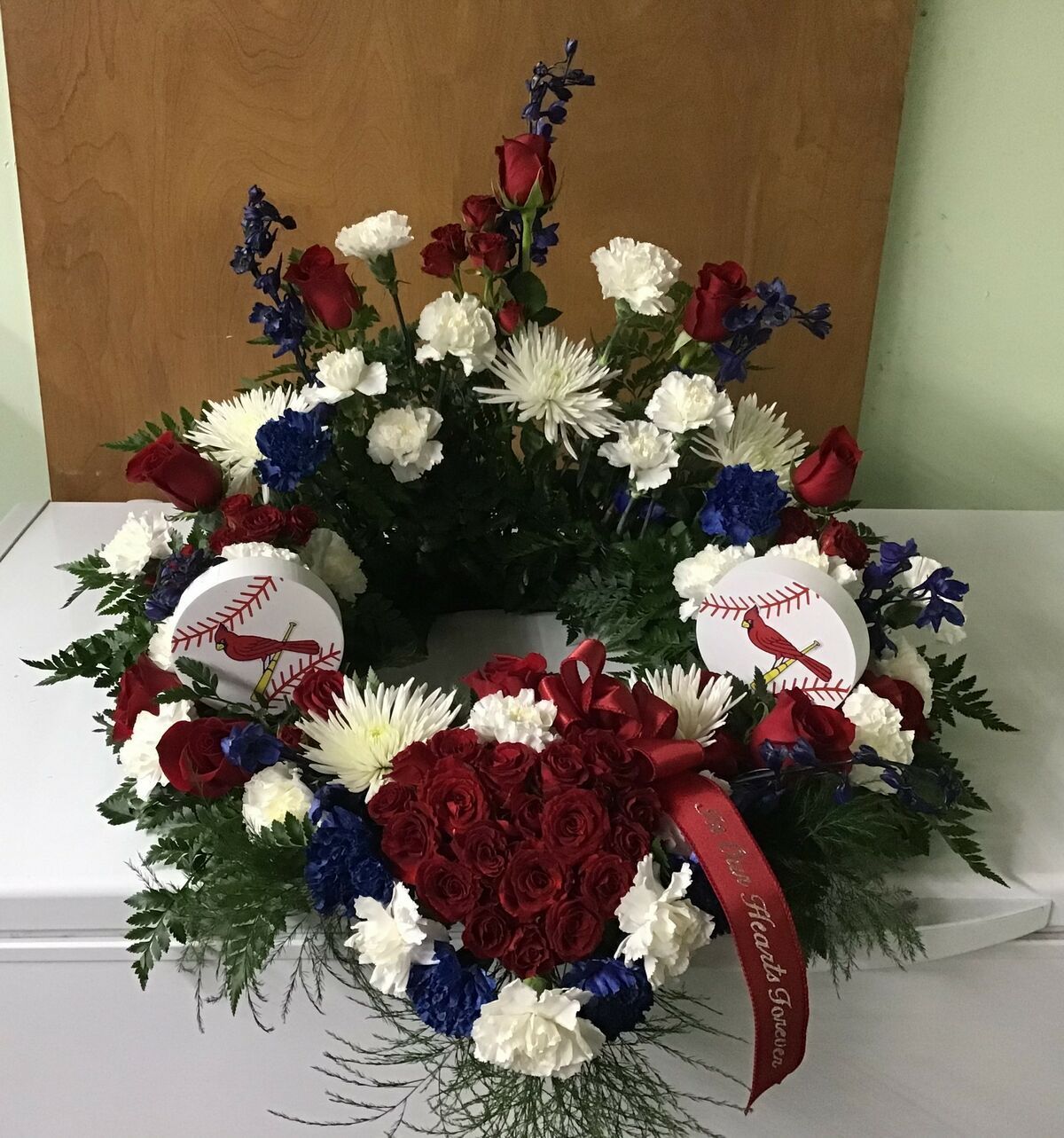 A wreath with red white and blue flowers and baseballs