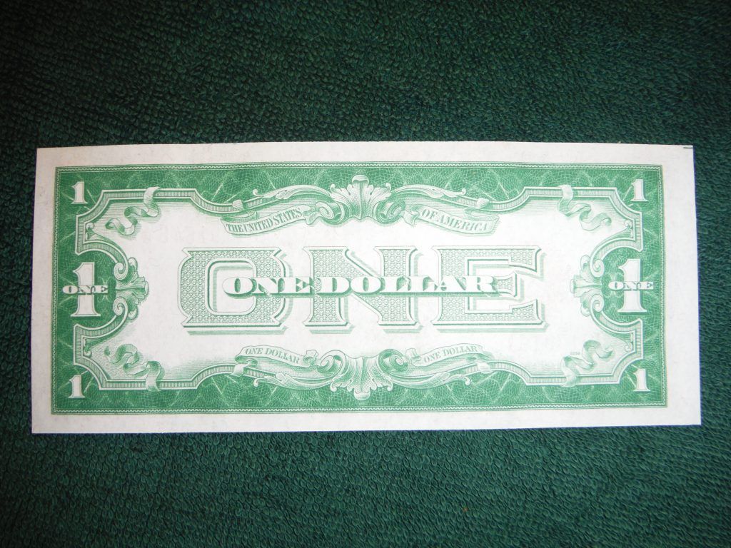 A green and white one dollar bill on a green surface