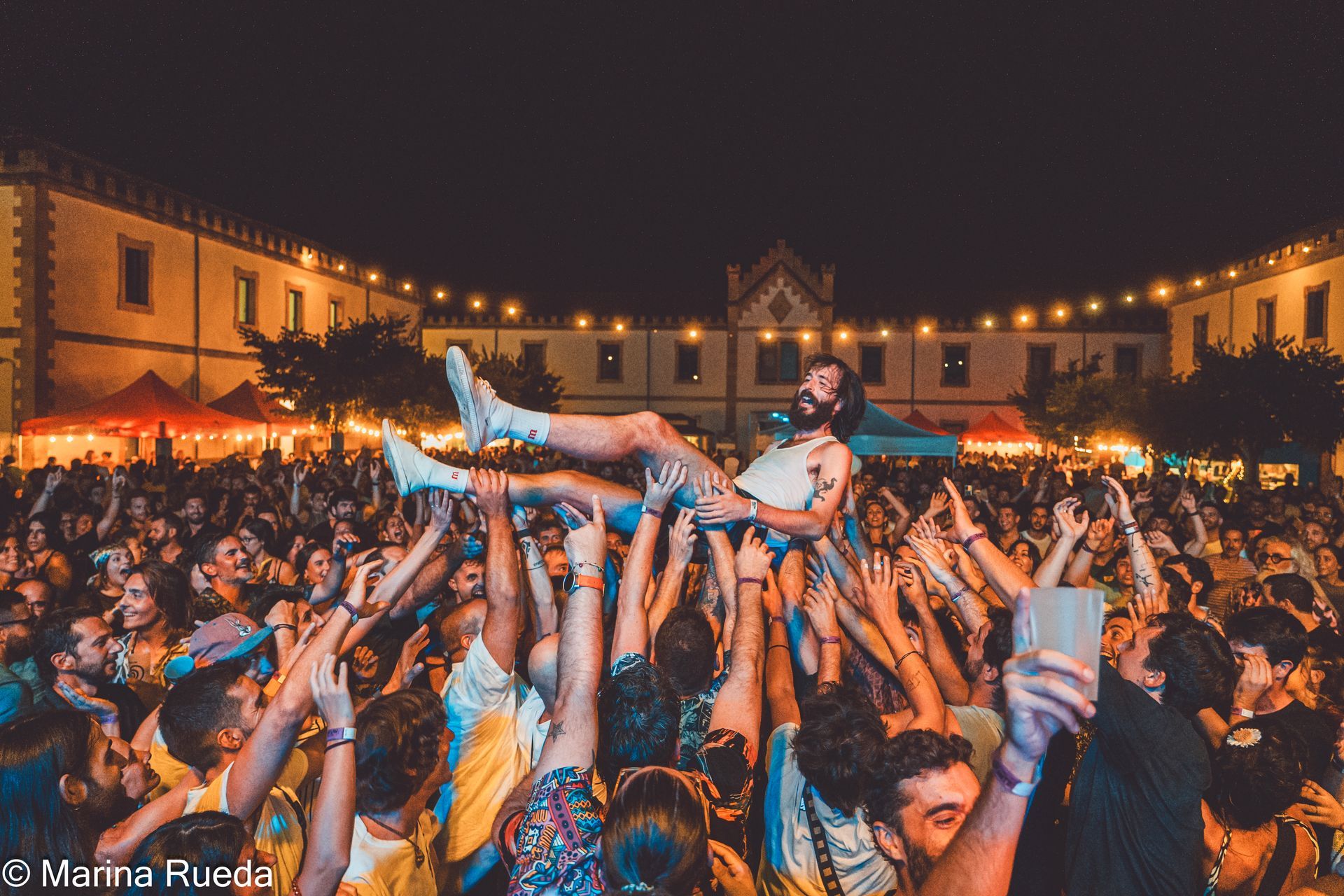 Un hombre es levantado en el aire por una multitud de personas en un concierto.