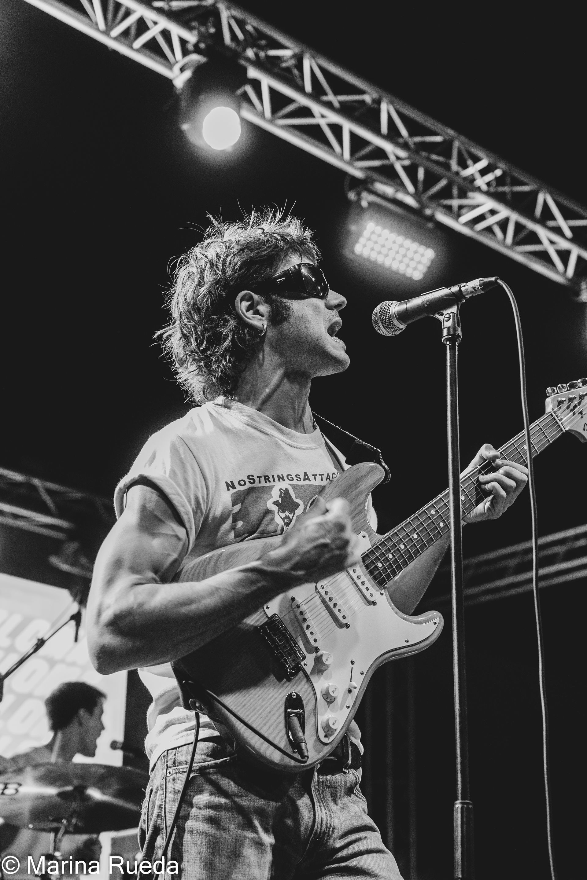 Un hombre está cantando en un micrófono mientras toca una guitarra.