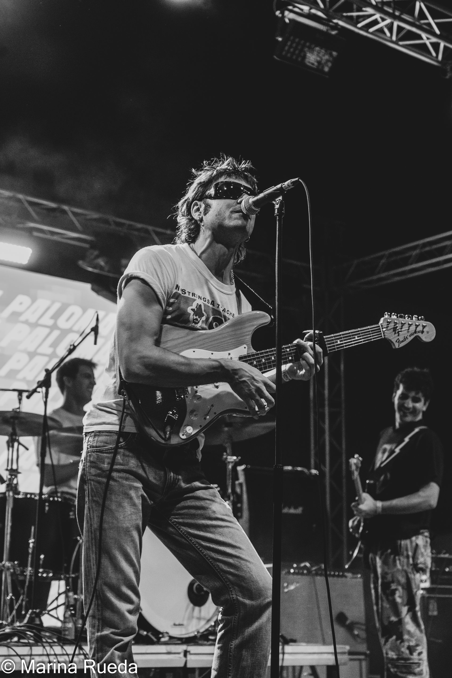 Un hombre canta en un micrófono mientras toca una guitarra en el escenario.
