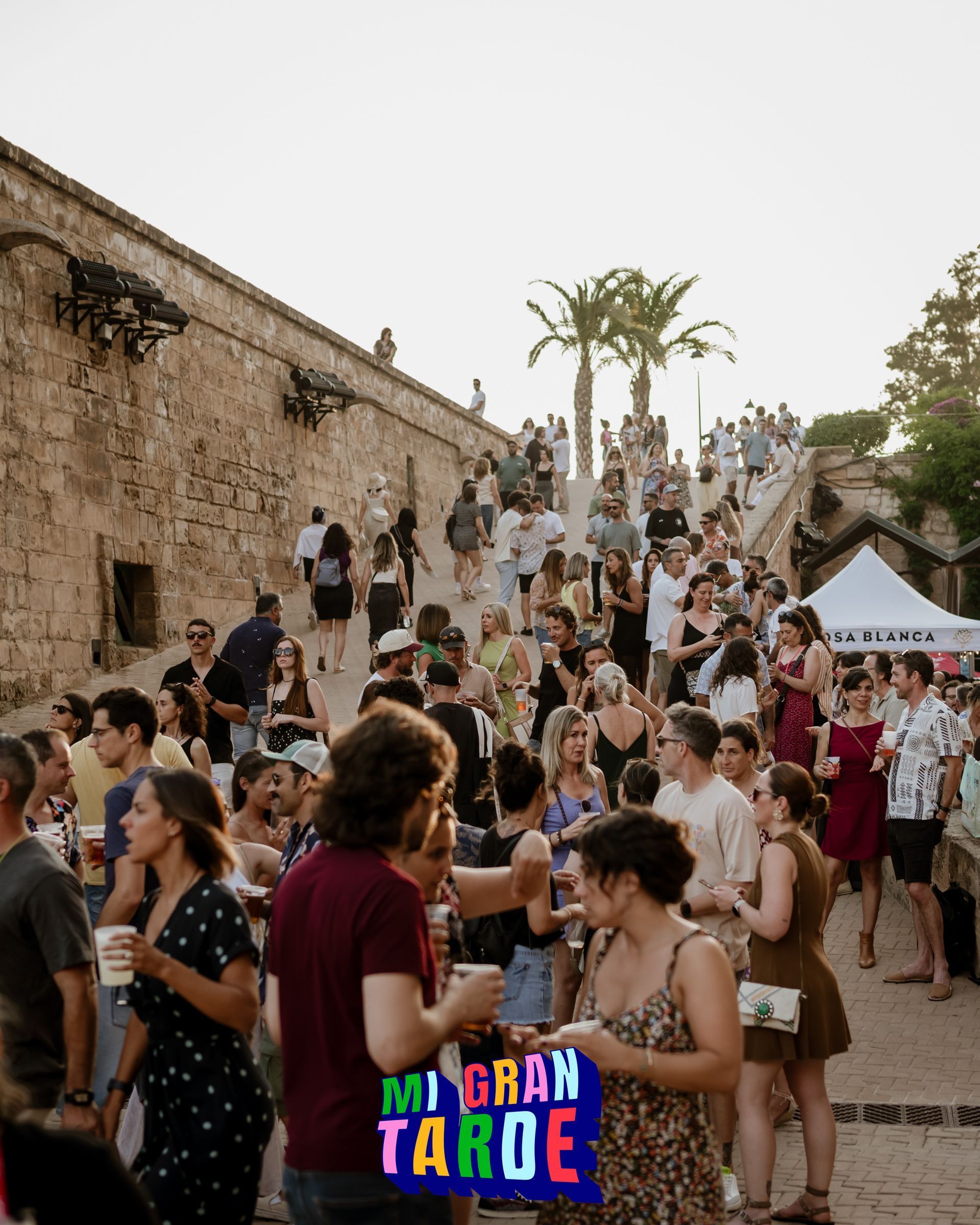Una multitud de personas se reúne frente a un cartel que dice mi gran tarde