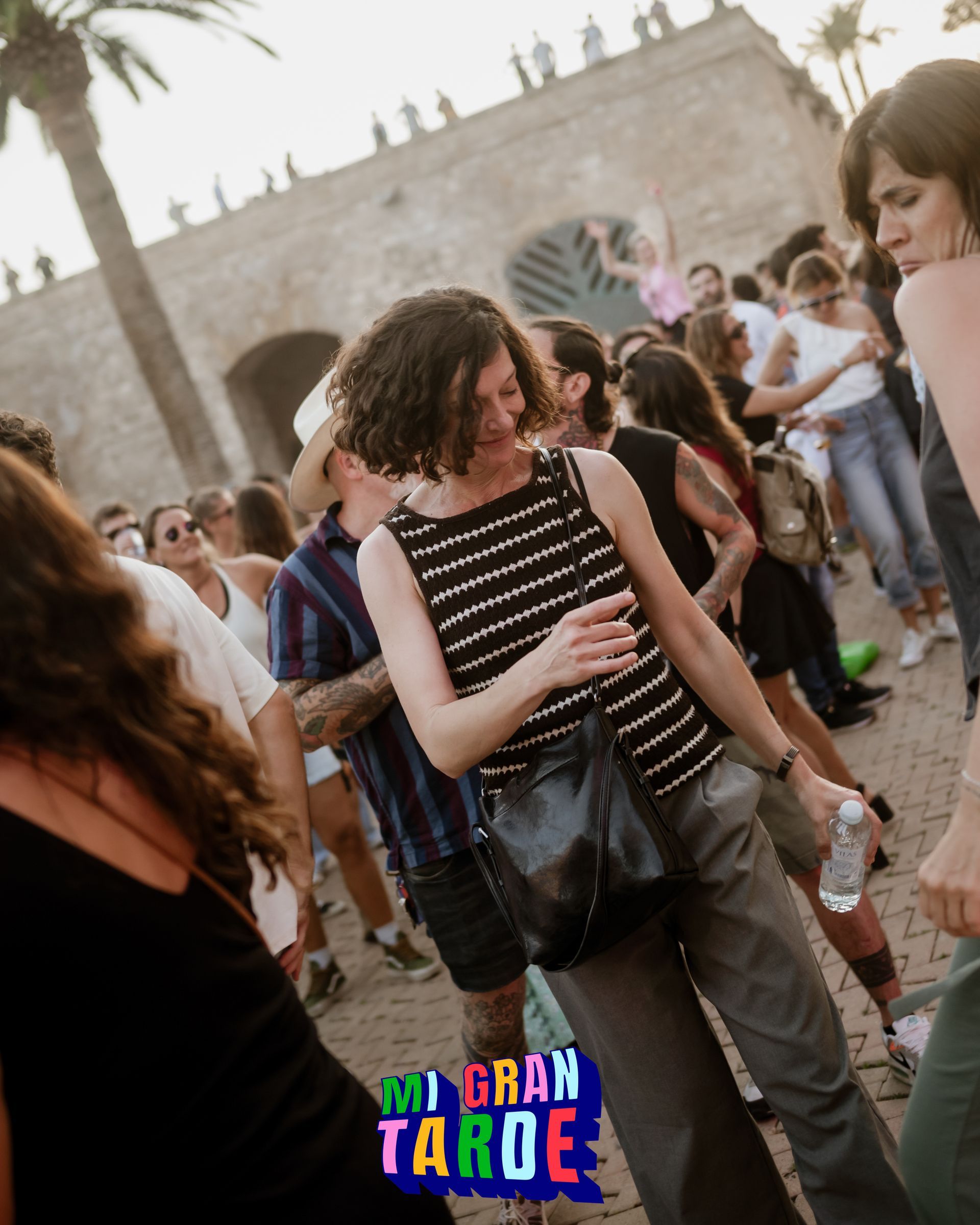 Una mujer está parada entre una multitud con un cartel que dice gran taroe
