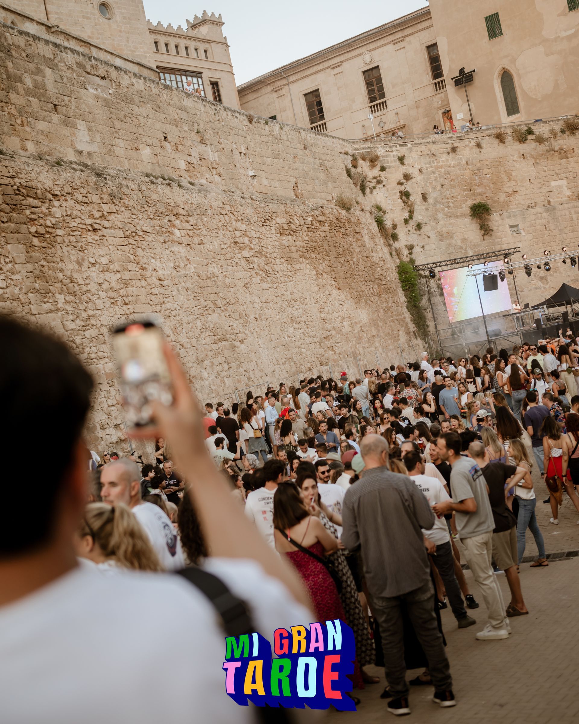 Un hombre está tomando una fotografía de una multitud de personas frente a un castillo.