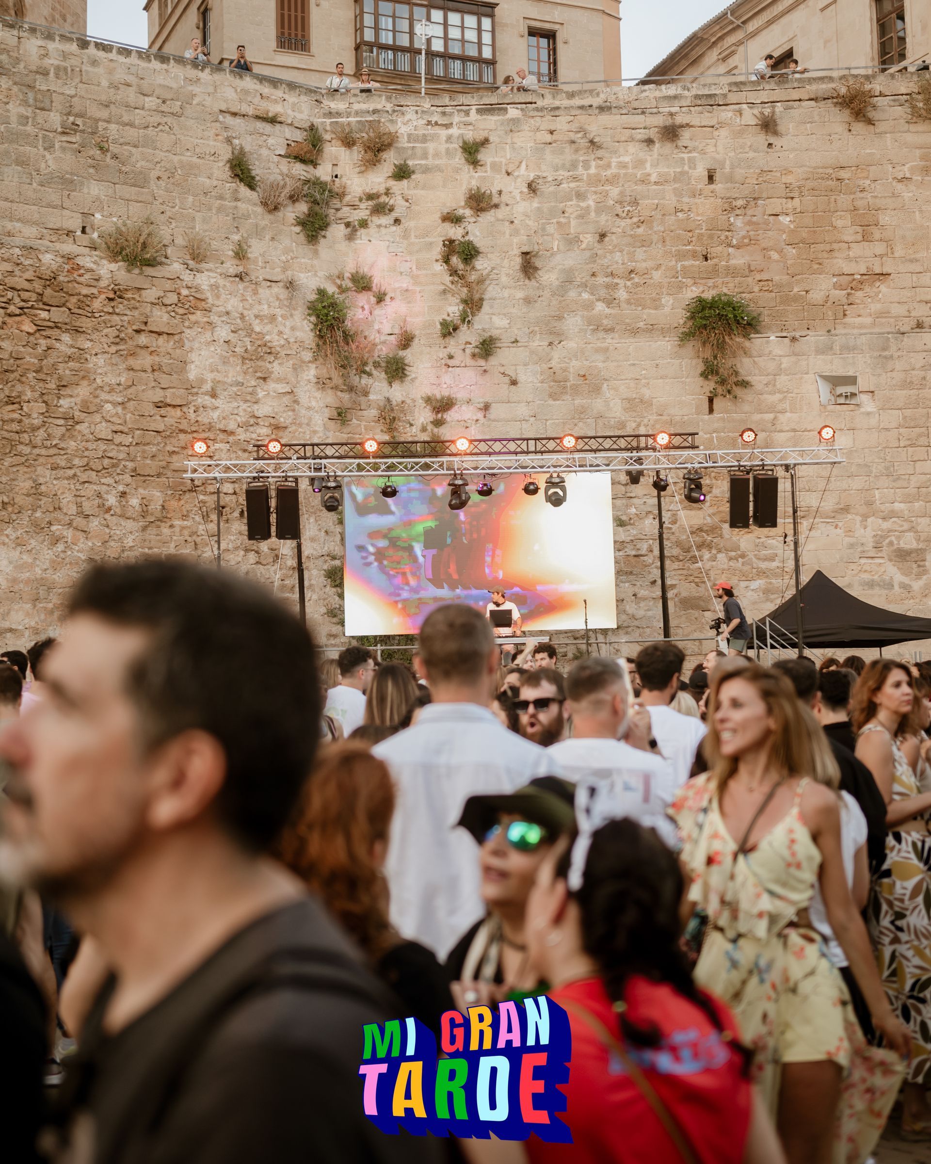 Una multitud de personas está reunida frente a una pantalla grande.
