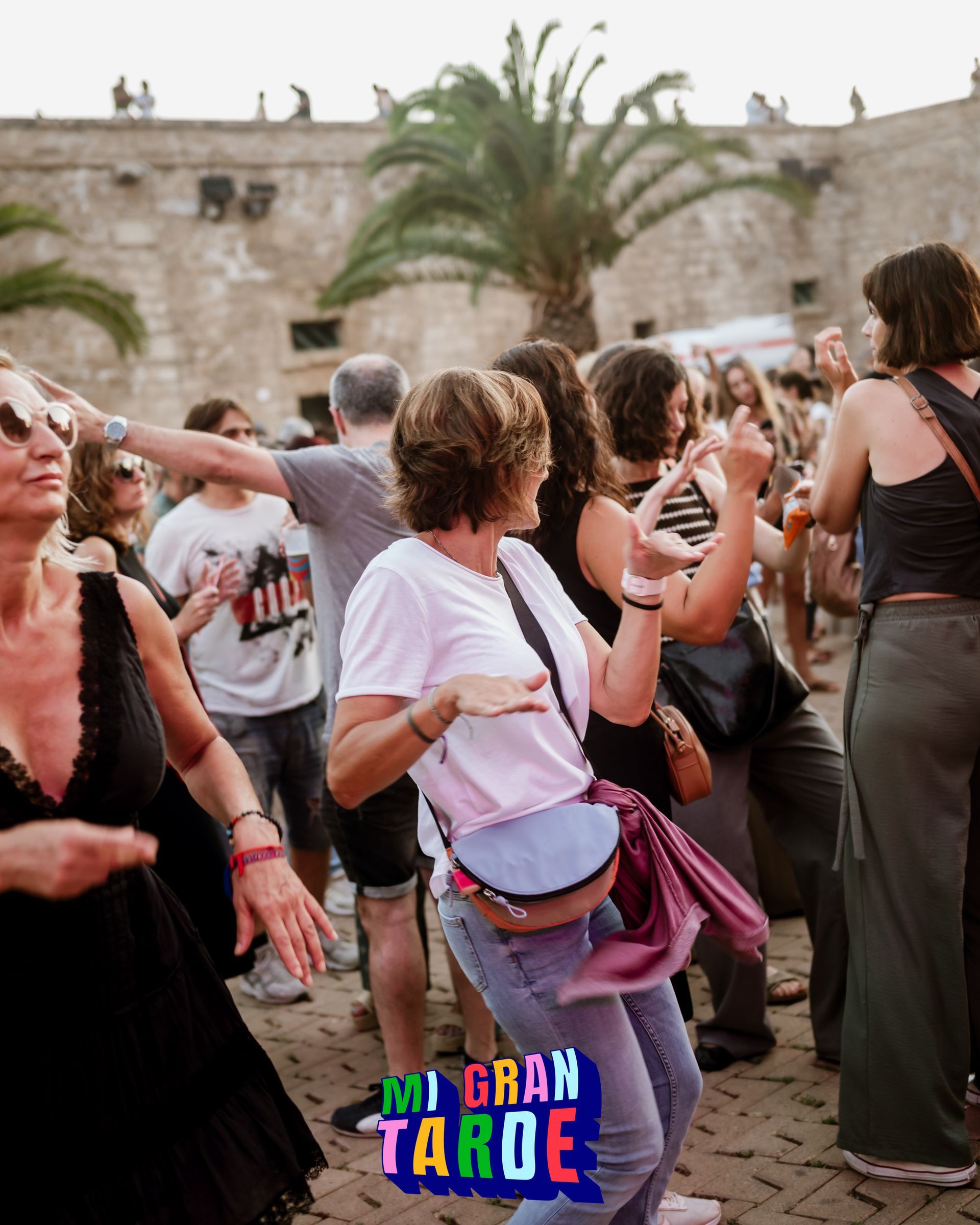 Un grupo de personas baila frente a un cartel que dice mi gran tarde