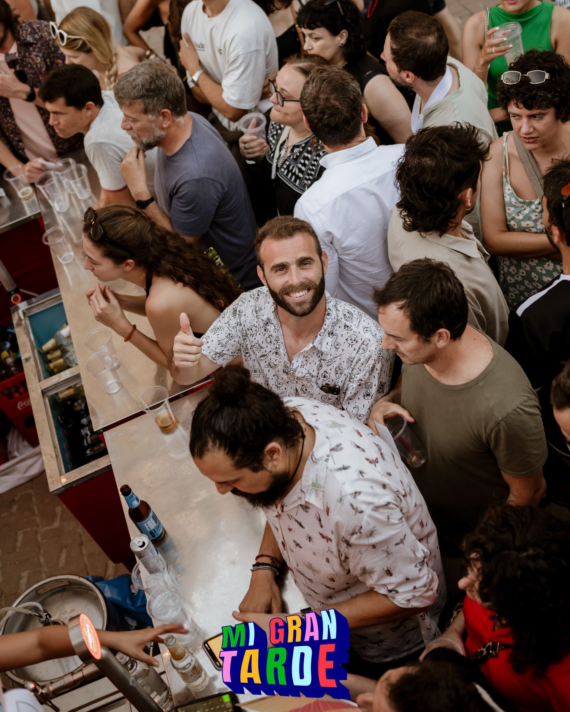 Un gran grupo de personas está reunido alrededor de un bar.