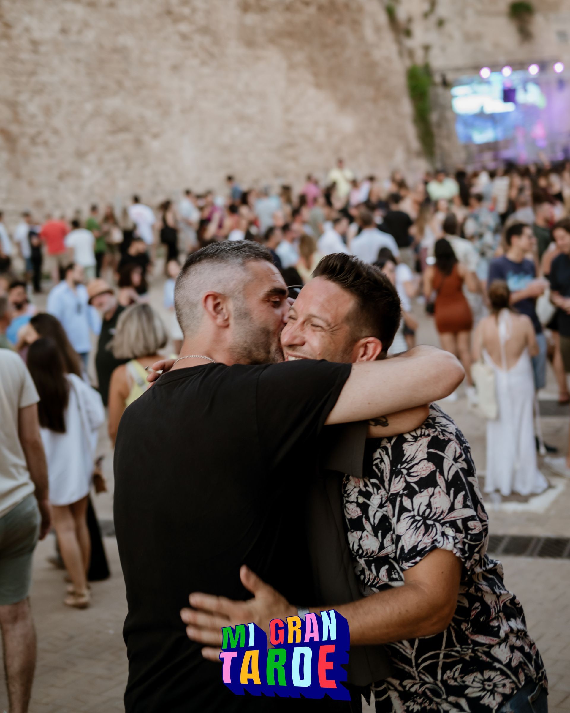 Dos hombres abrazándose frente a una multitud con un cartel que dice Gran Tahoe