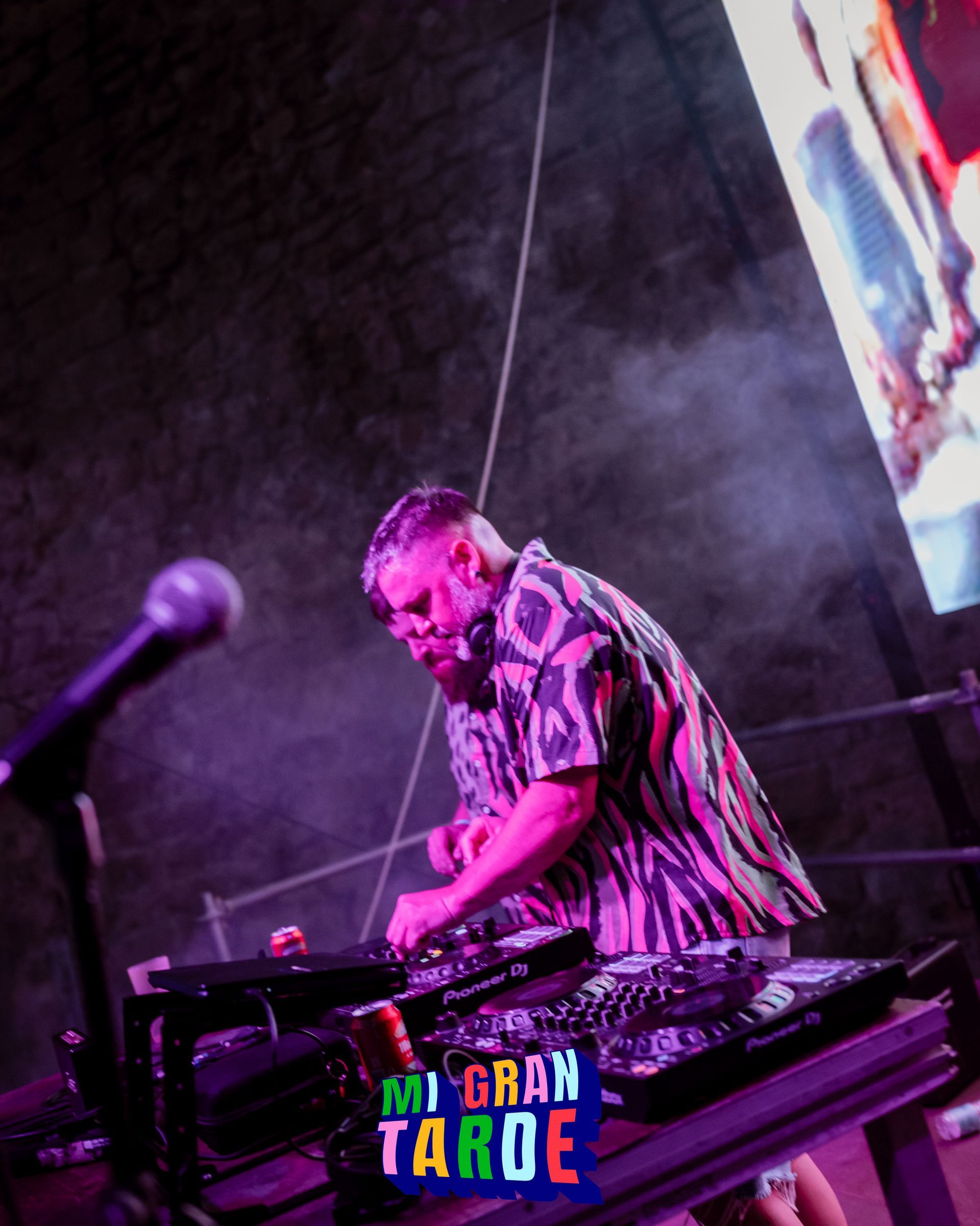 Un hombre está tocando un set de DJ frente a un cartel que dice Mi gran tarde.