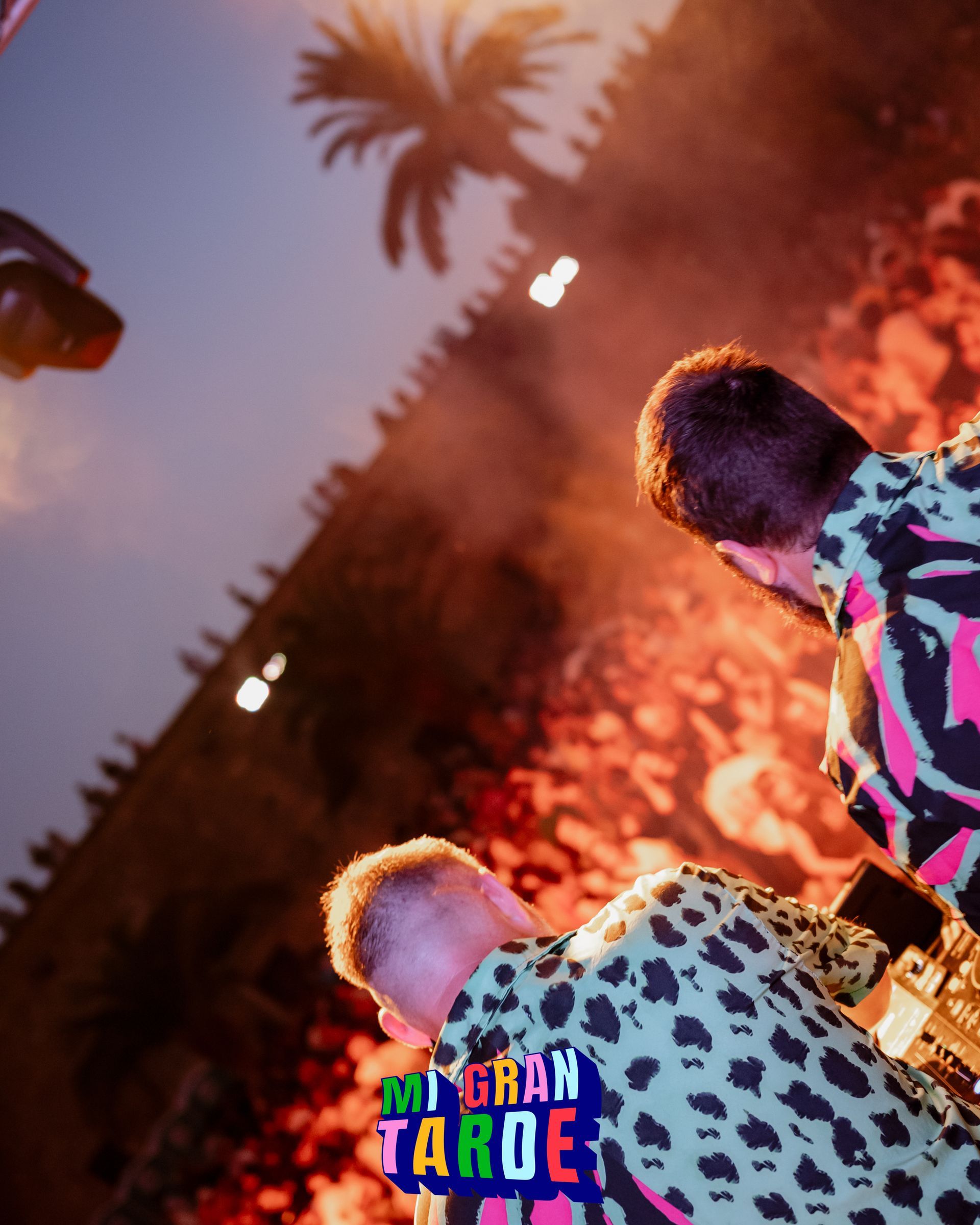 Dos hombres de pie frente a una multitud con un cartel que dice gran taroe