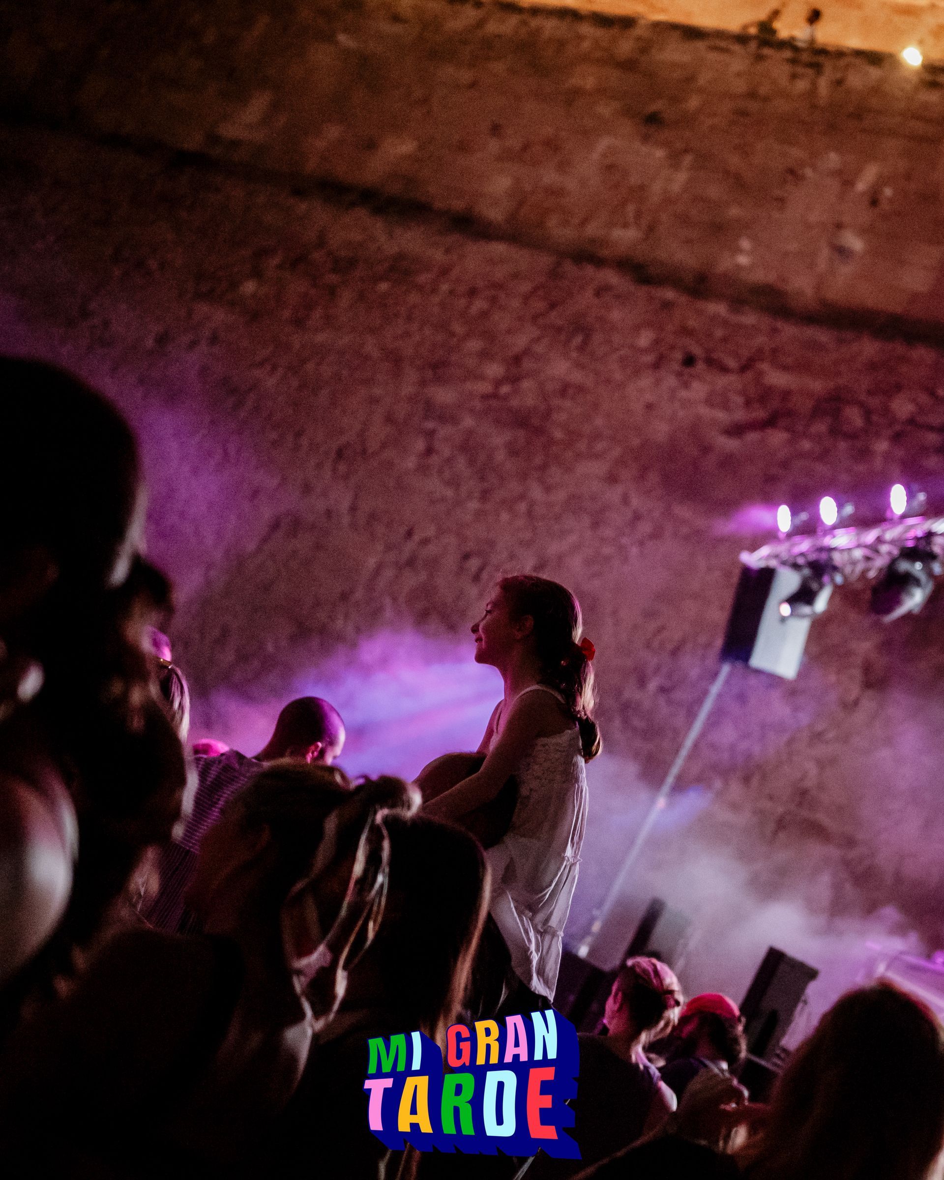 Un grupo de personas está bailando en una habitación oscura con un cartel que dice mi gran taroe