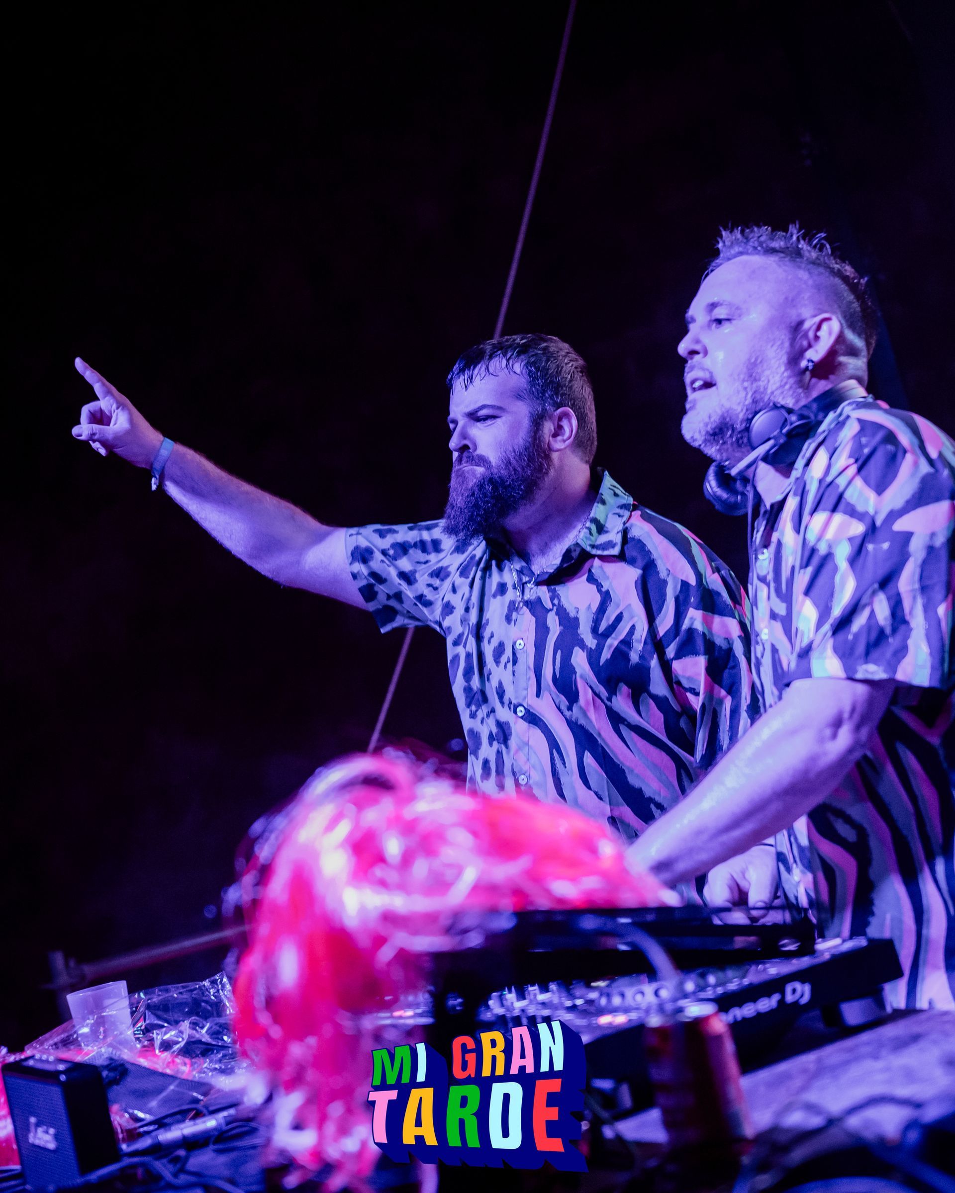 Dos hombres están tocando música en un escenario en una habitación oscura.
