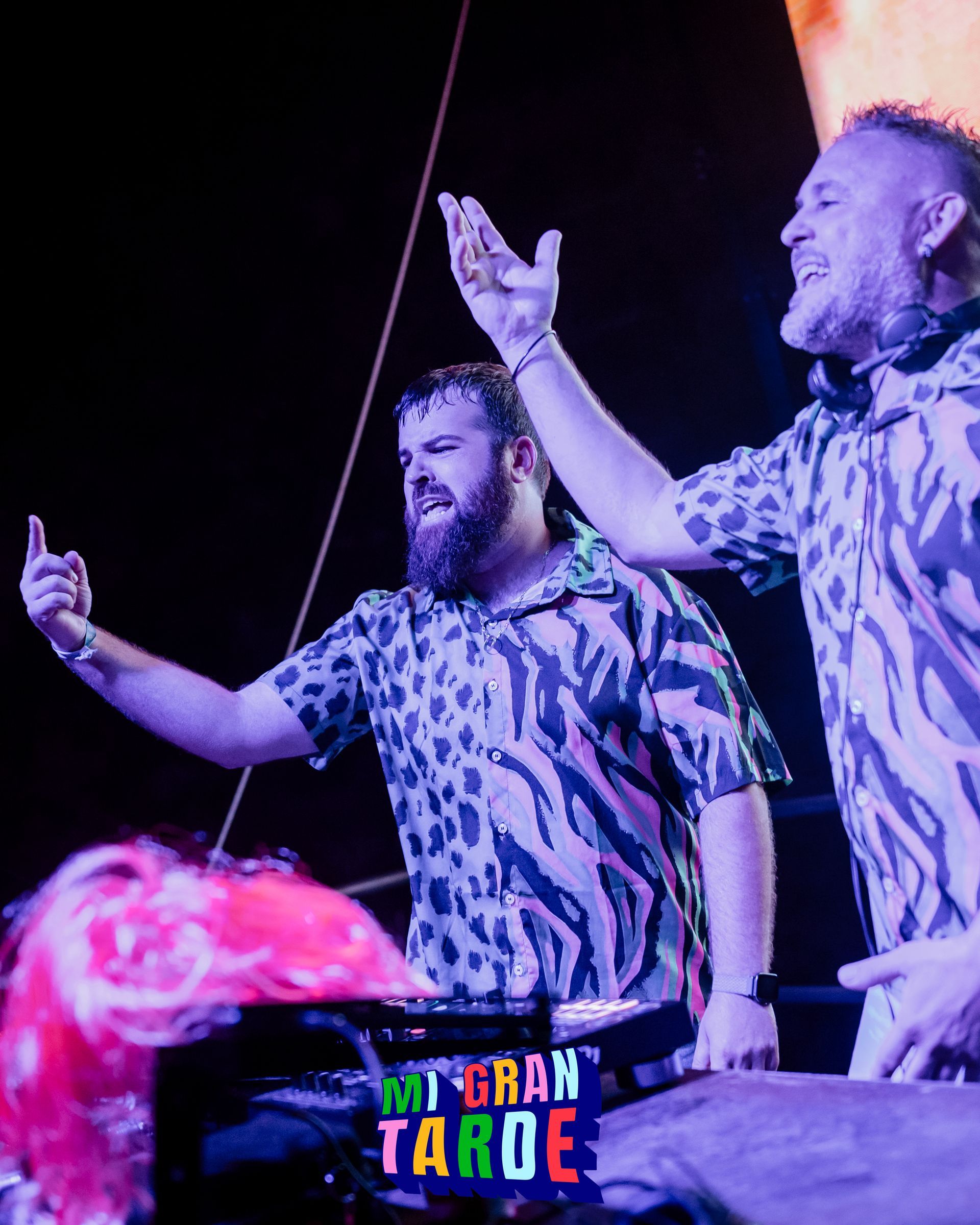 Dos hombres están de pie en un escenario con los brazos en el aire.
