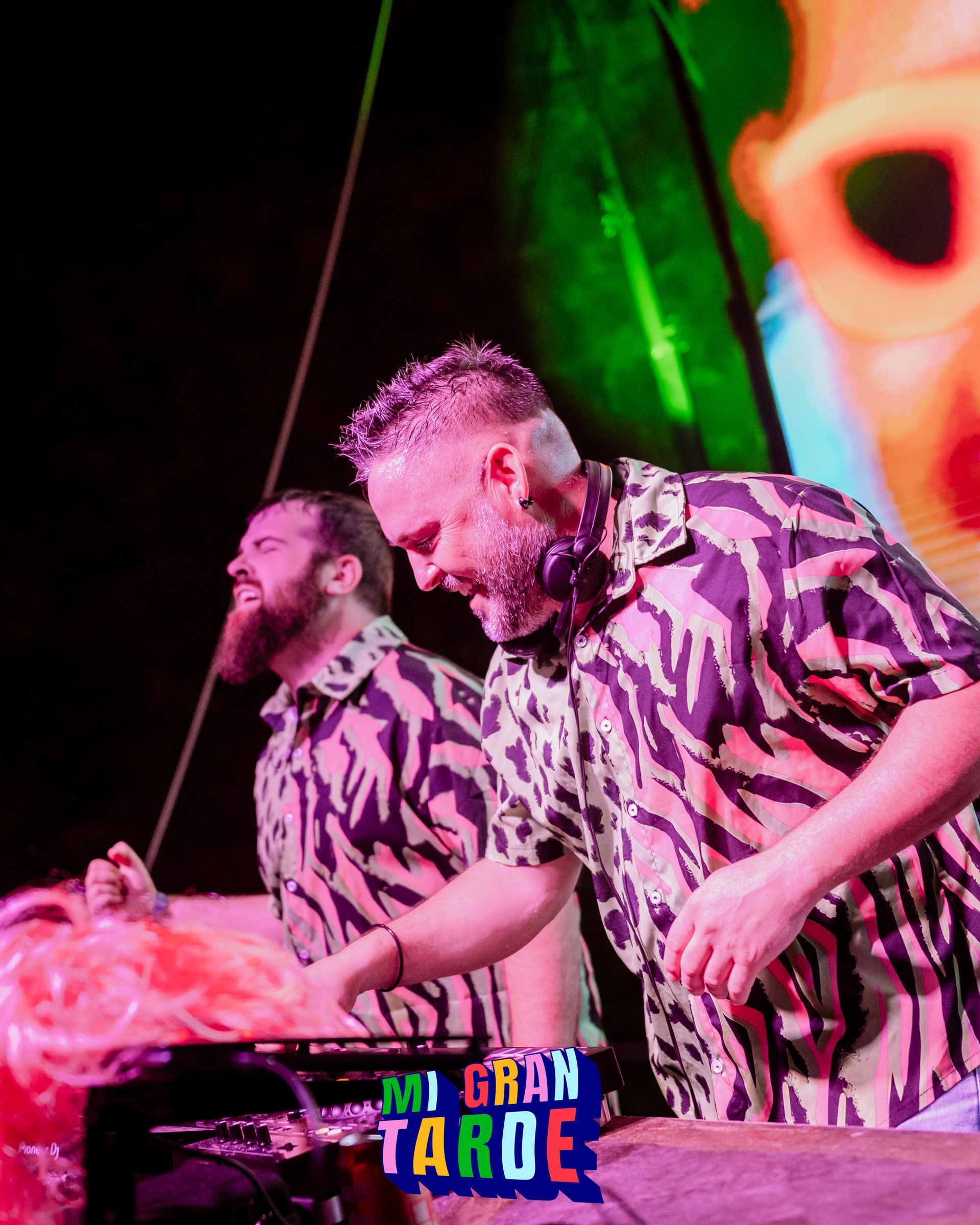 Dos hombres con camisetas con estampado de cebra están parados uno al lado del otro en un escenario.