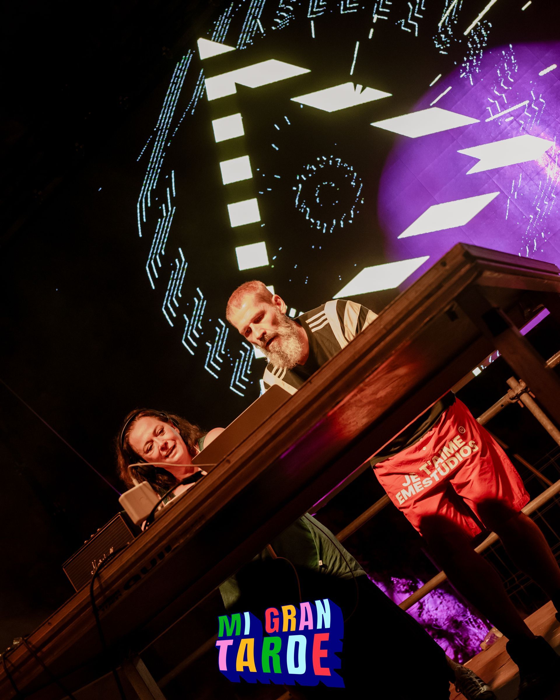 Un hombre y una mujer están sentados en una mesa frente a una pantalla que dice mi gran tarde
