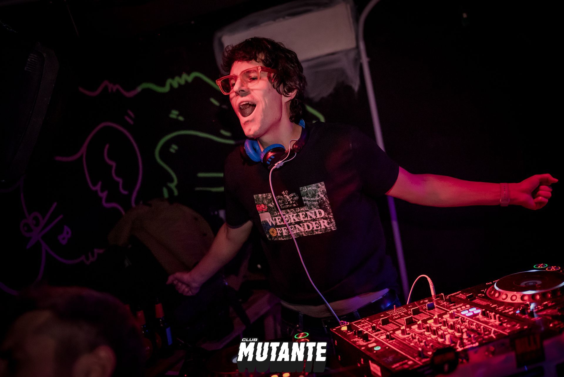 Un hombre está parado frente a un mezclador de DJ en una habitación oscura.