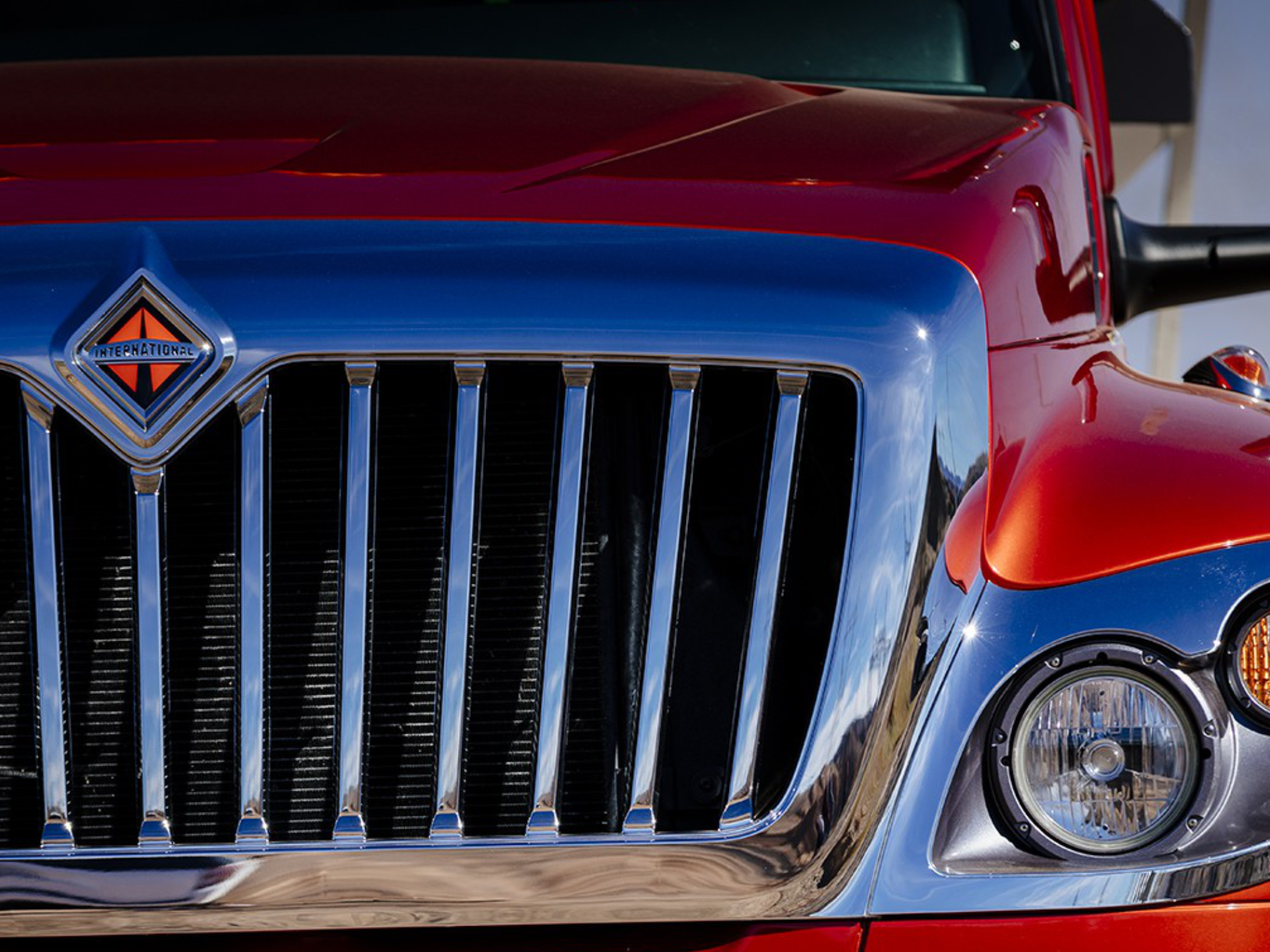 A red international truck is parked in front of a building