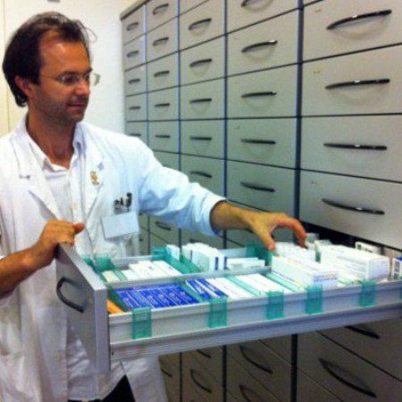 un uomo con un camice bianco mentre apre un cassetto con dentro dei farmaci