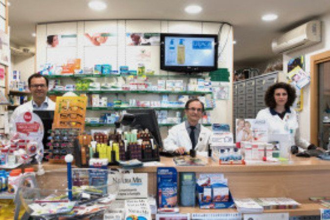 interno di una farmacia con due uomini e una donna con un  camice bianco