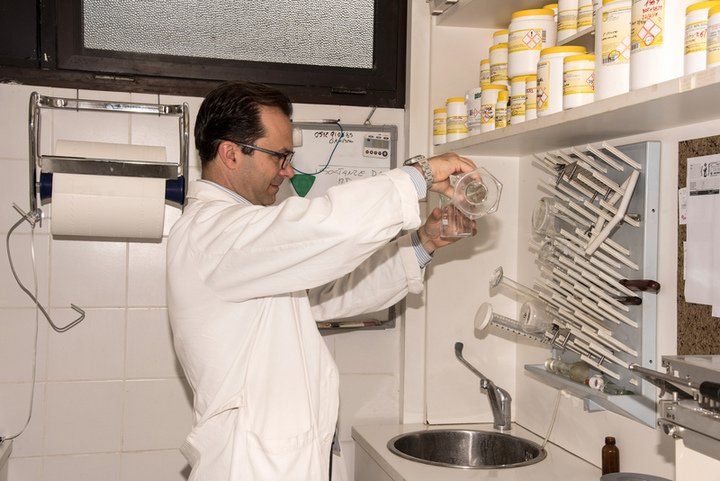 un uomo con un camice bianco in un laboratorio e vista delle mensole con dei barattoli