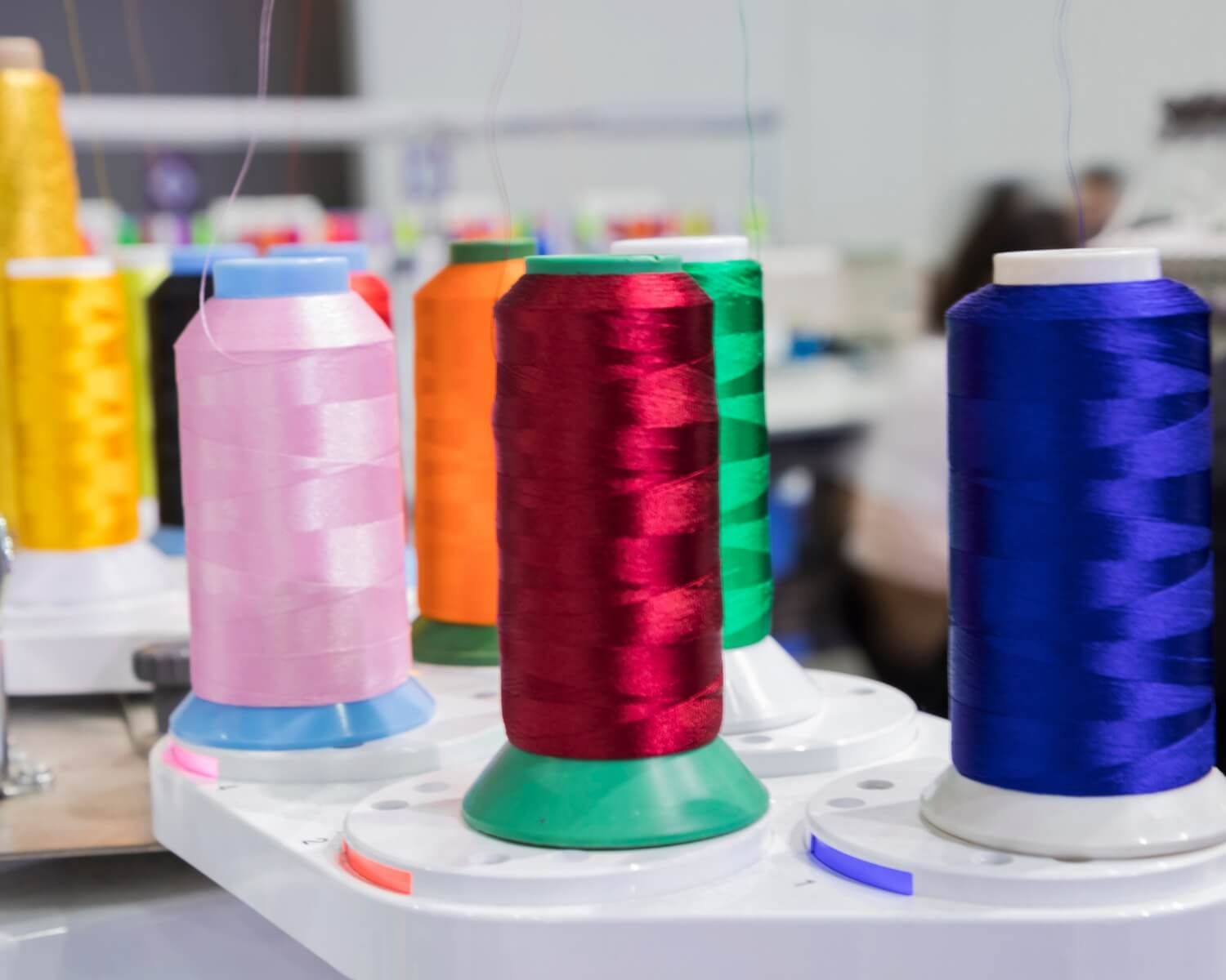 A bunch of different colored spools of thread on a table