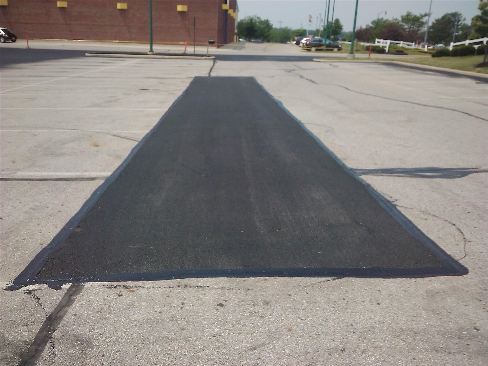 A black asphalt road with a brick building in the background