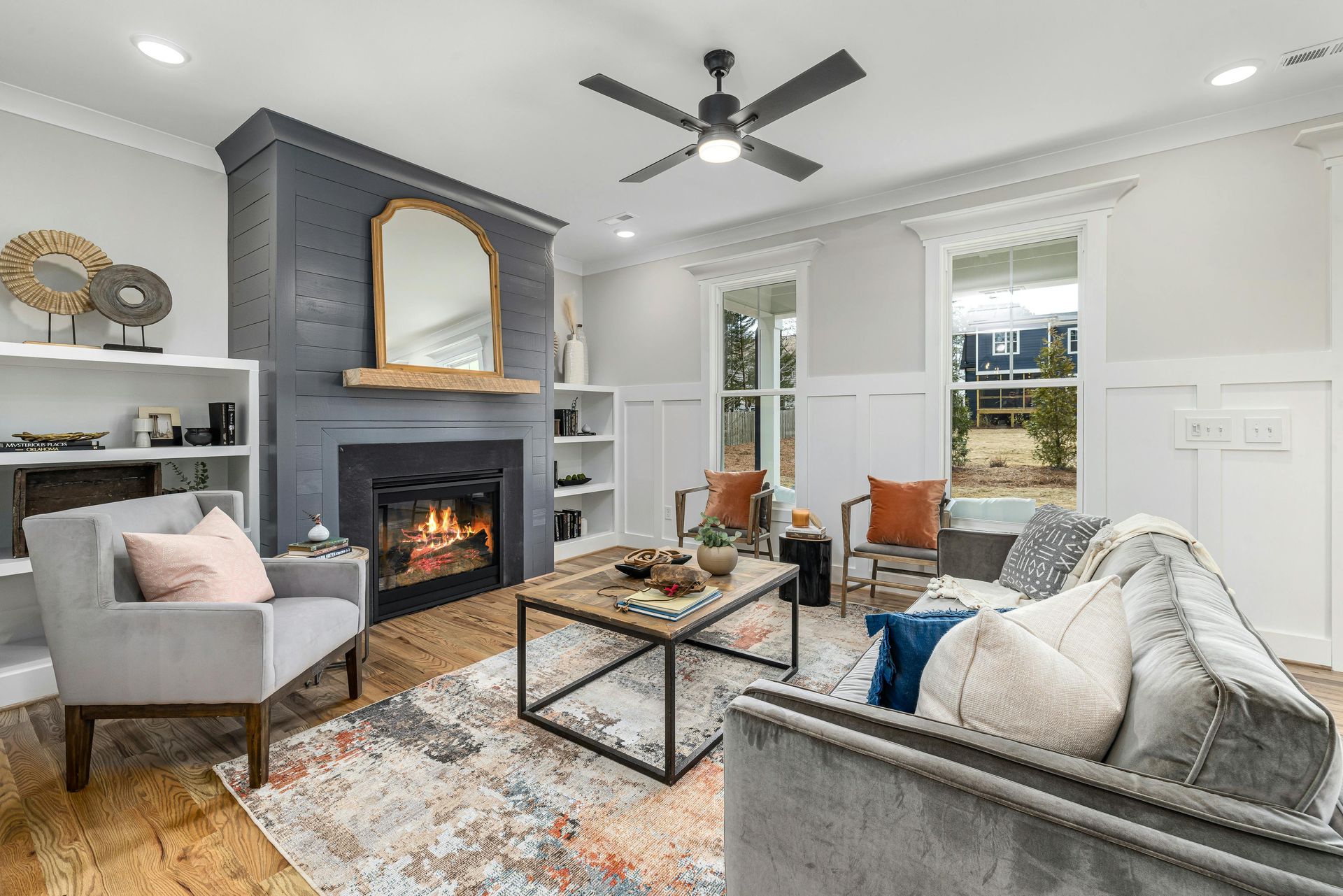 A living room with a fireplace , couch , chair , coffee table and ceiling fan.