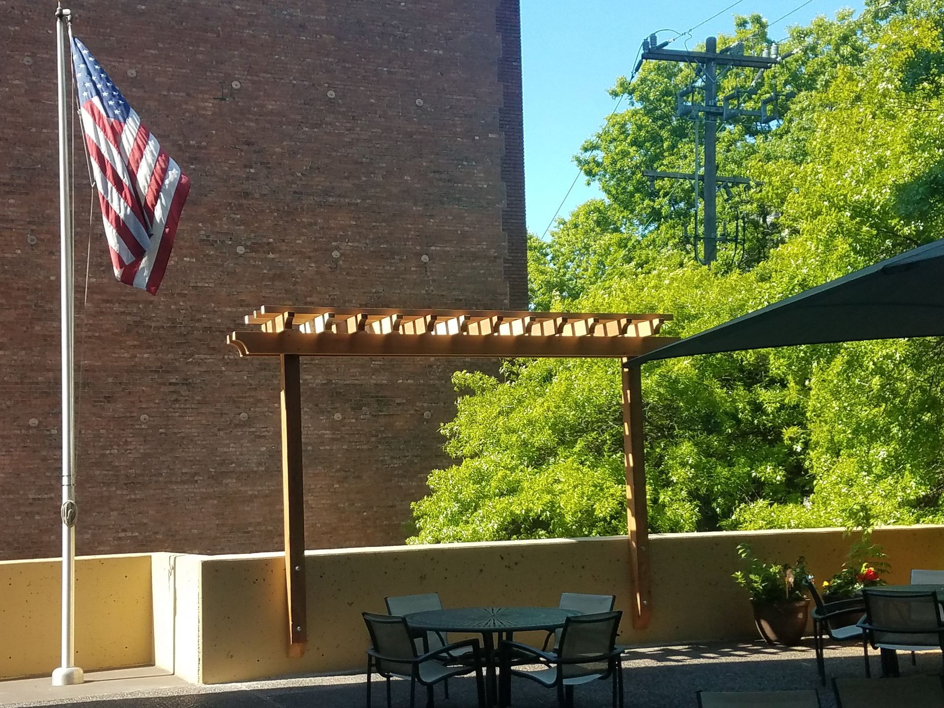 American flag, wooden pergola, and outdoor dining area on a sunny day.