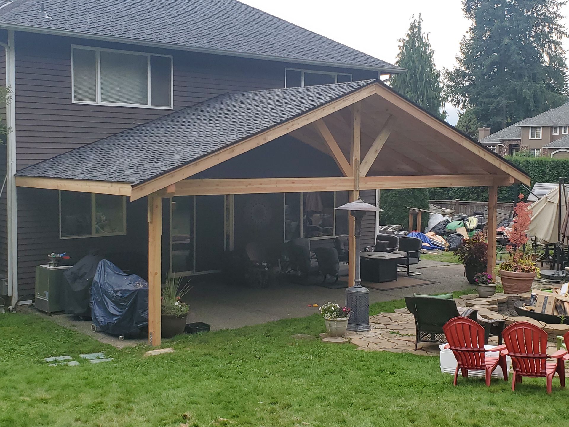 Brown house with a covered patio, backyard with chairs and a fire pit.