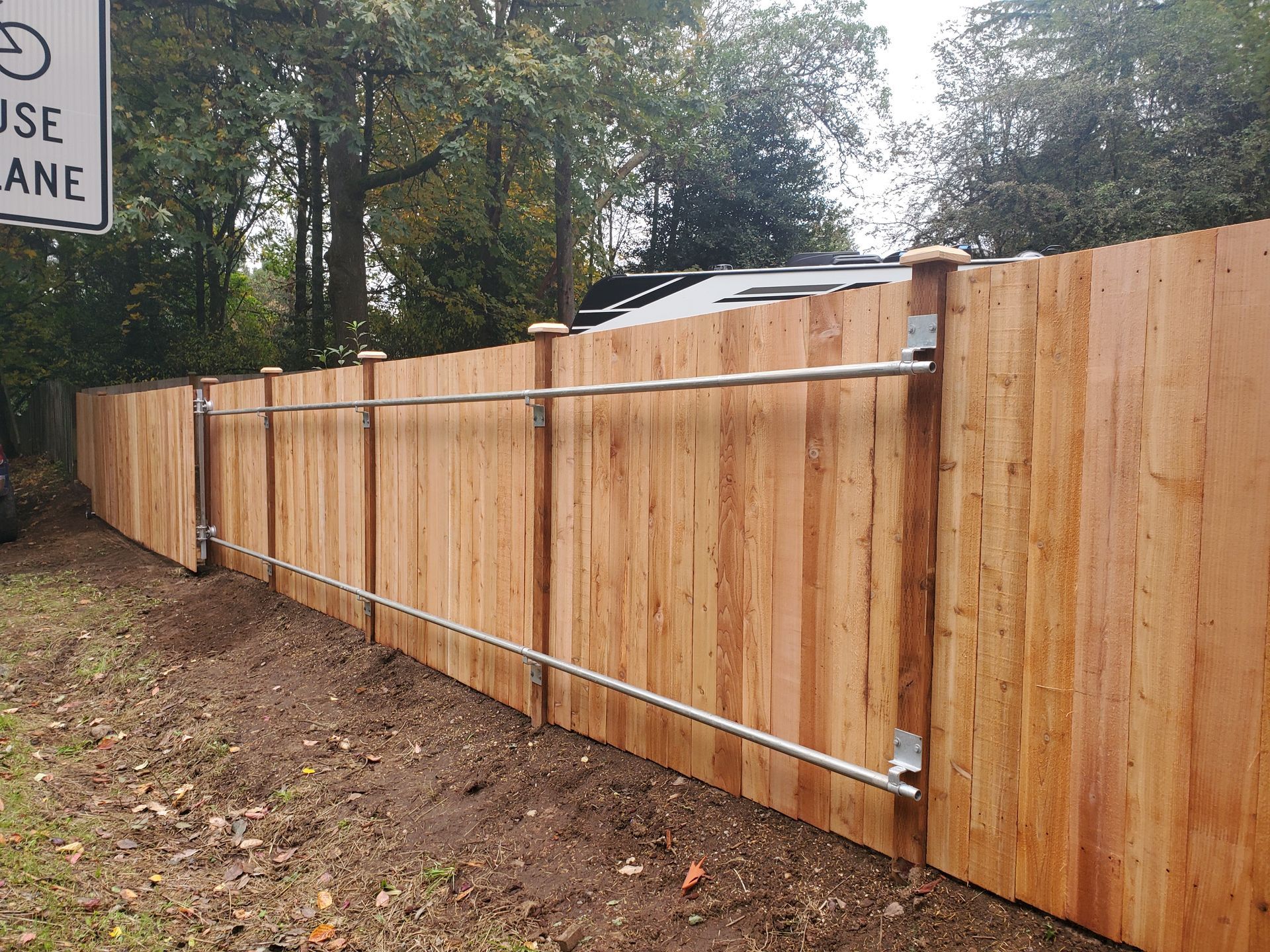 Wooden fence with metal handrail along roadside.