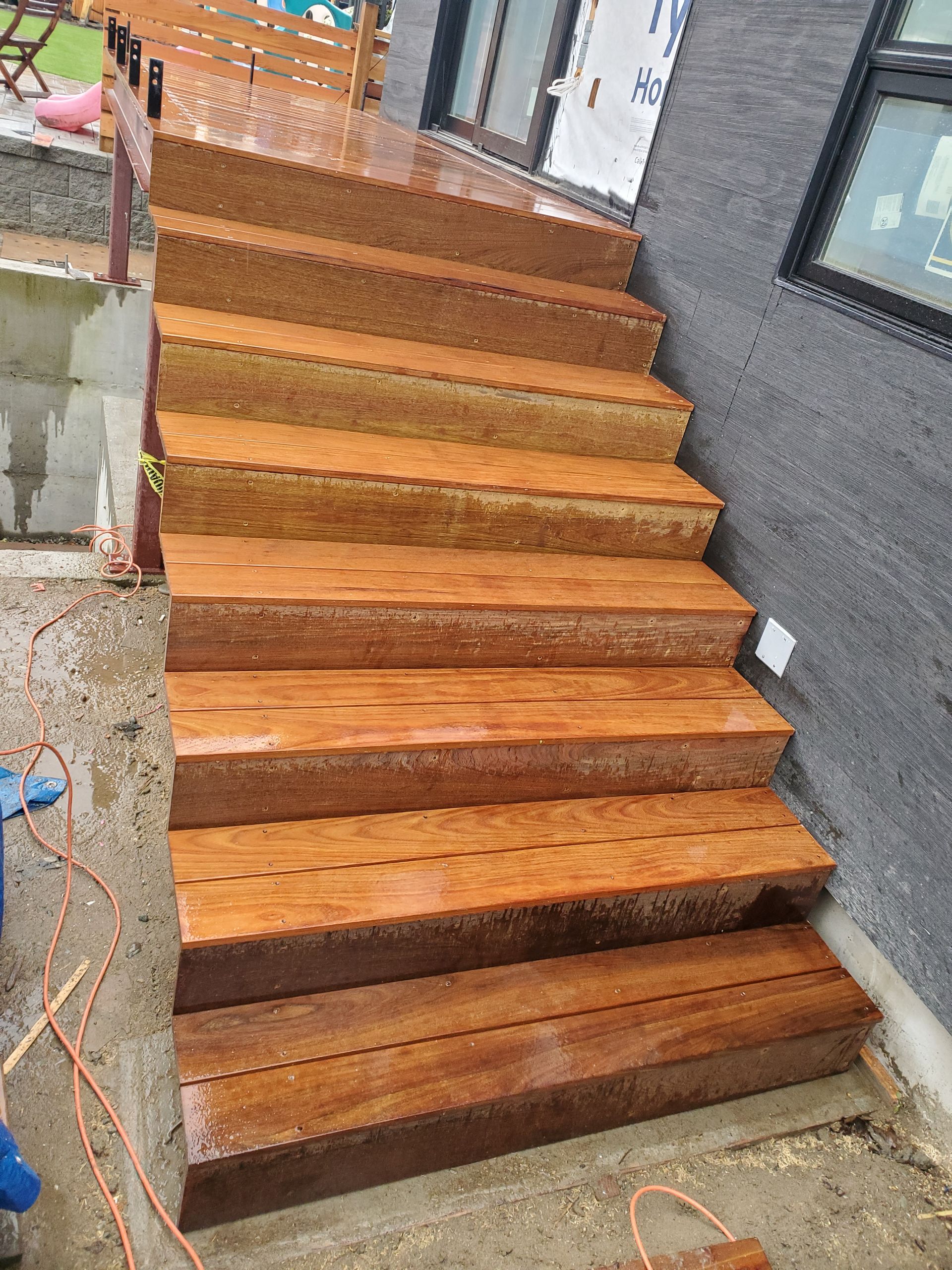 Wooden outdoor stairs leading up to a house with a gray exterior.