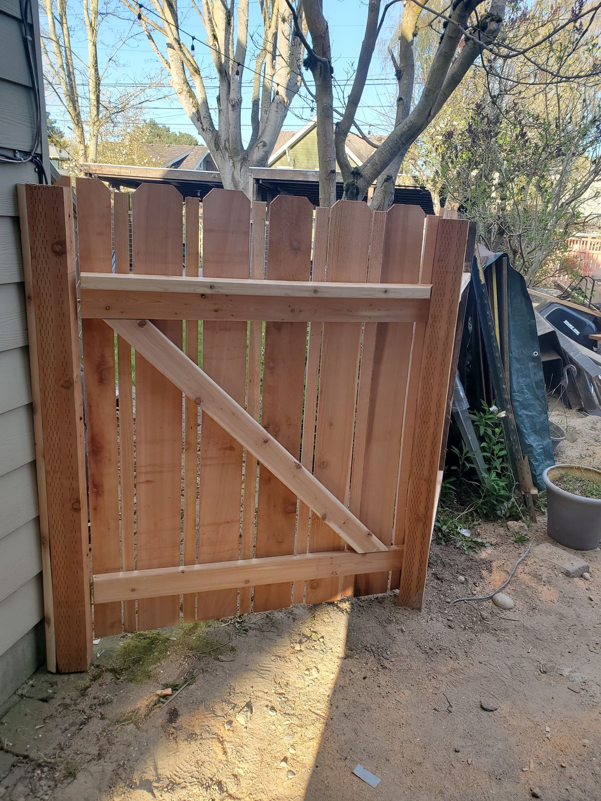 Wooden gate with a diagonal brace, in a yard.