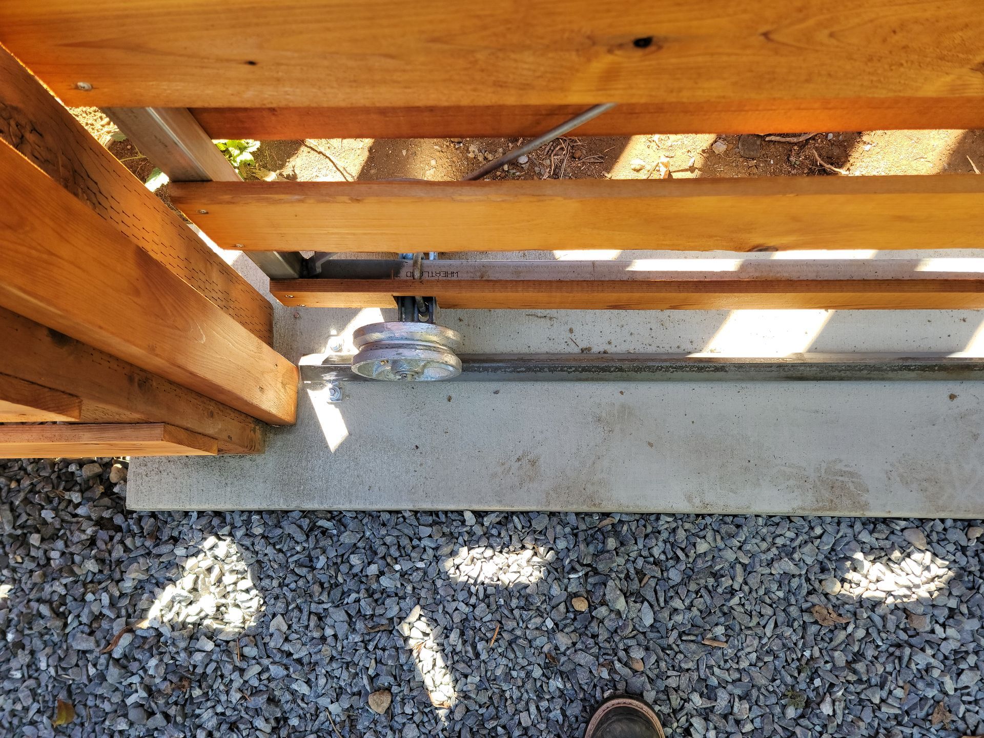 Wooden gate with concrete base and gravel ground.