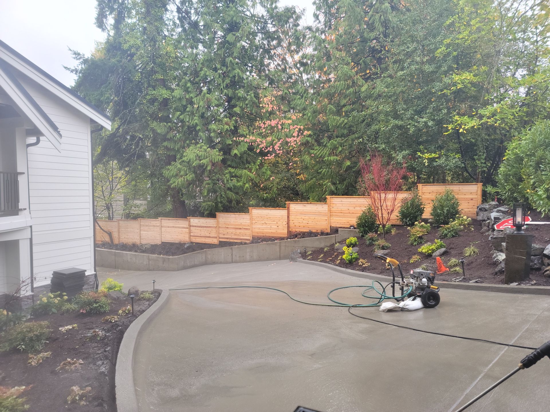 Concrete driveway with a new wooden fence and landscaping.