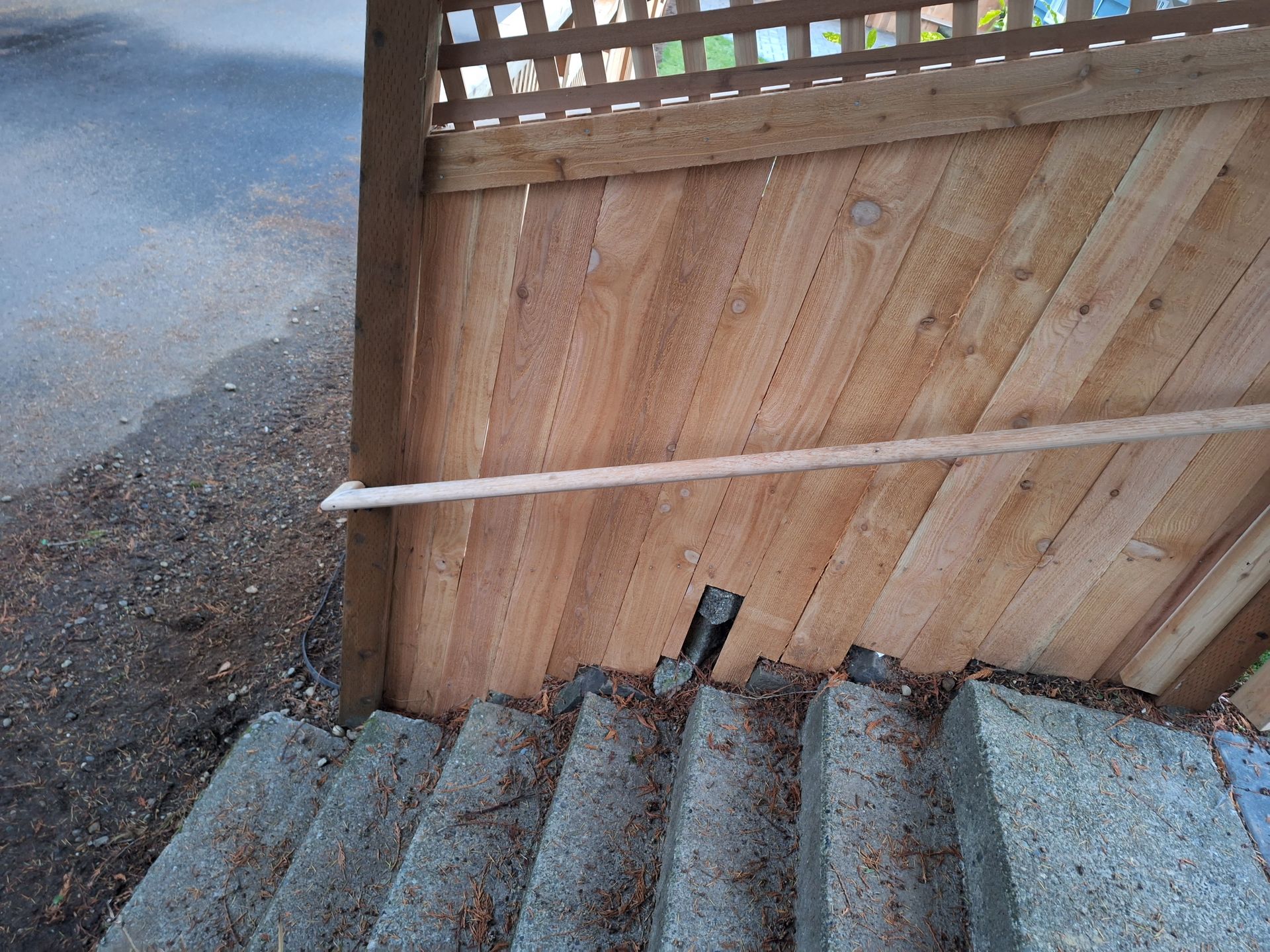 Concrete stairs leading down, with wooden fence and lattice above.