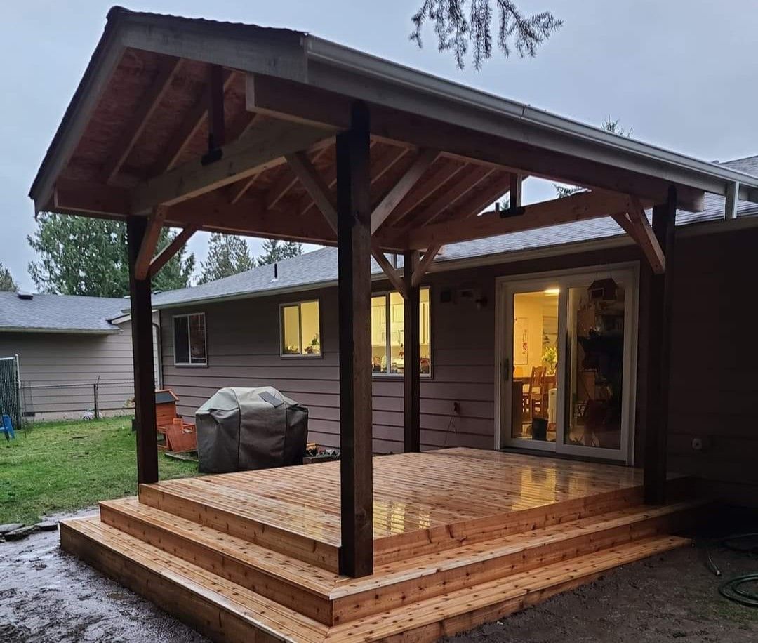 Wooden deck with a covered roof, attached to a house with a sliding glass door.