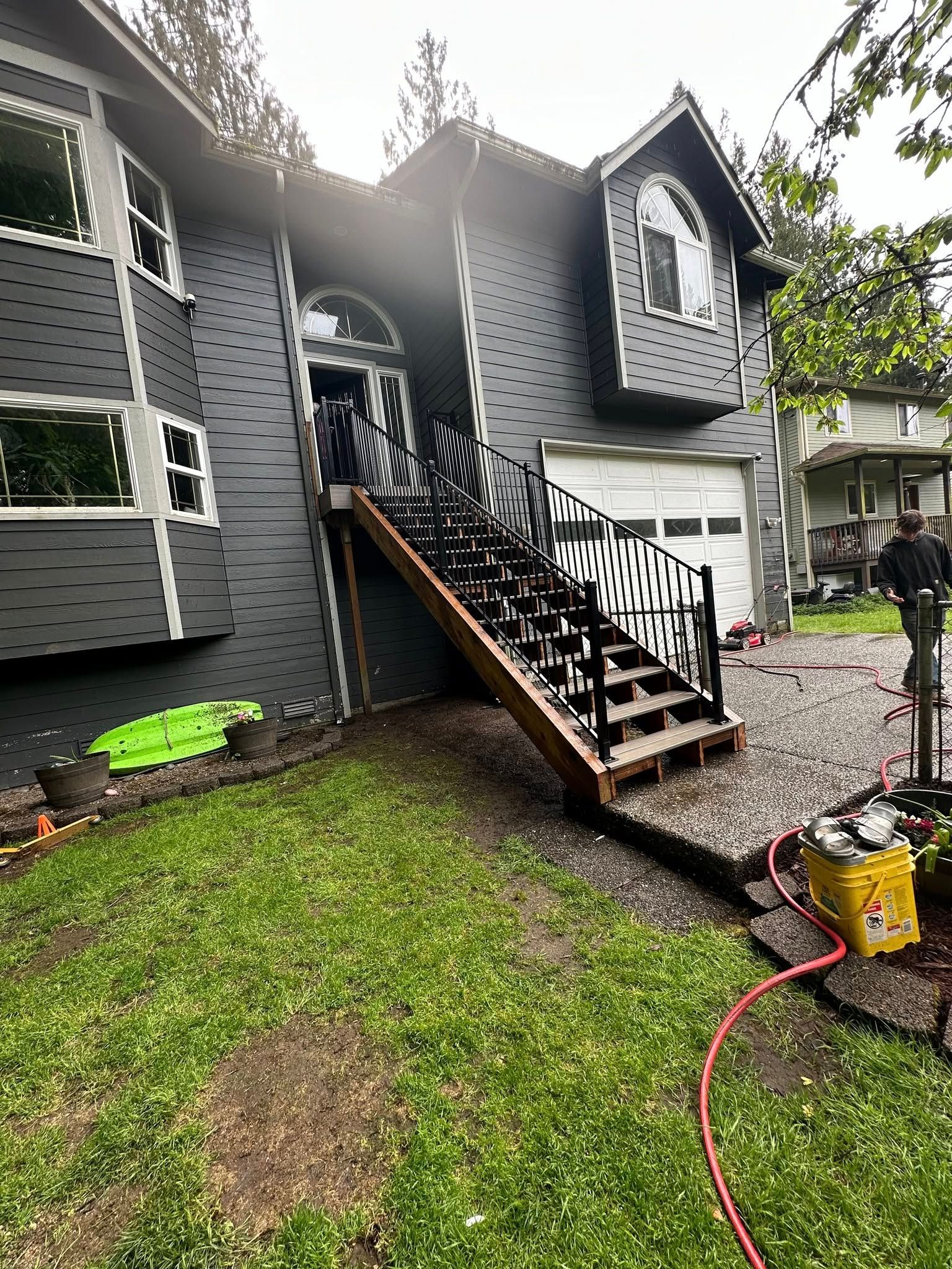 House exterior with dark siding, front steps with black railing, evidence of fire damage near the entrance.