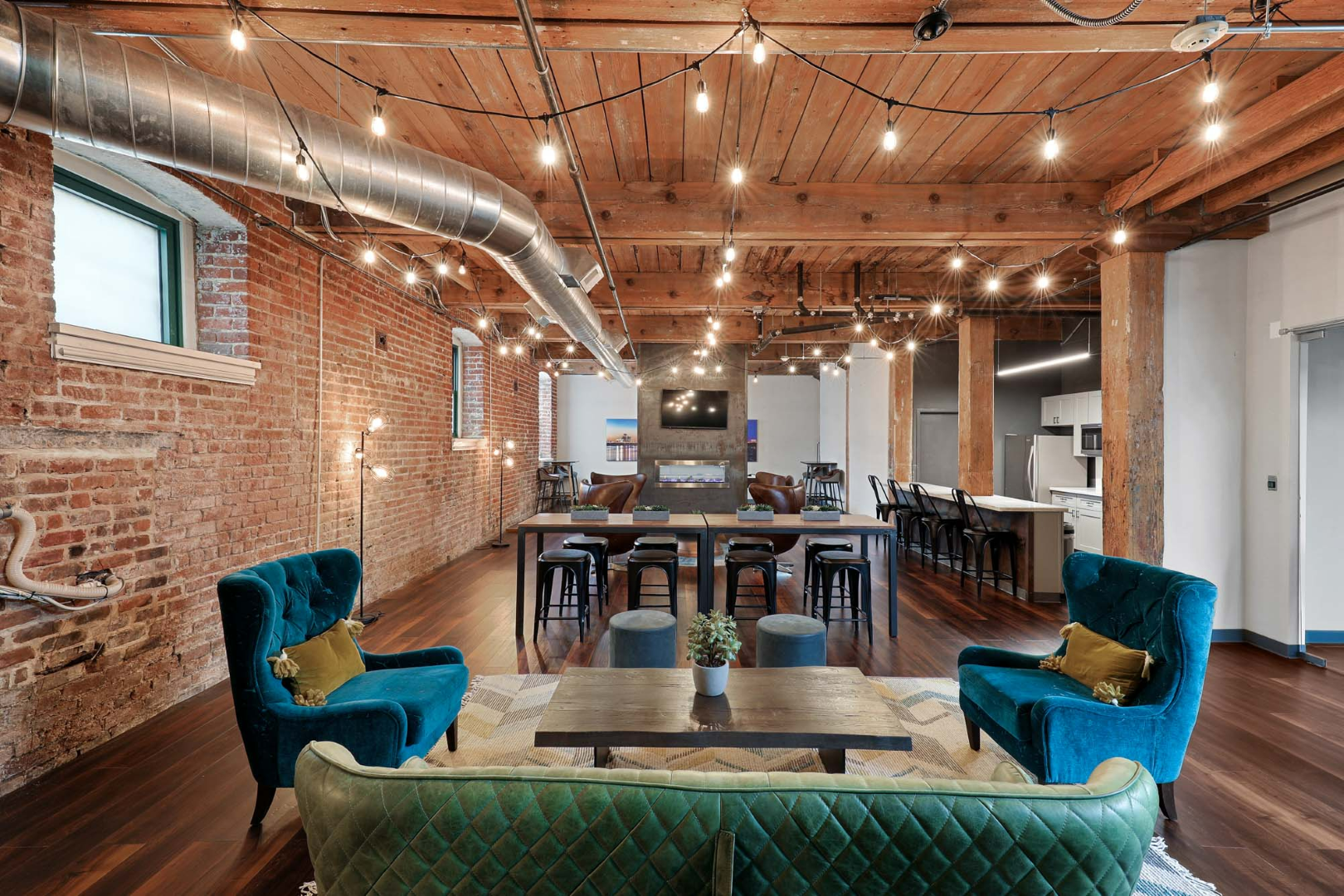 The apartment clubhouse with a green couch, blue chairs, and a table at The River Lofts at Tobacco Row offers apartments for rent in Richmond, VA.