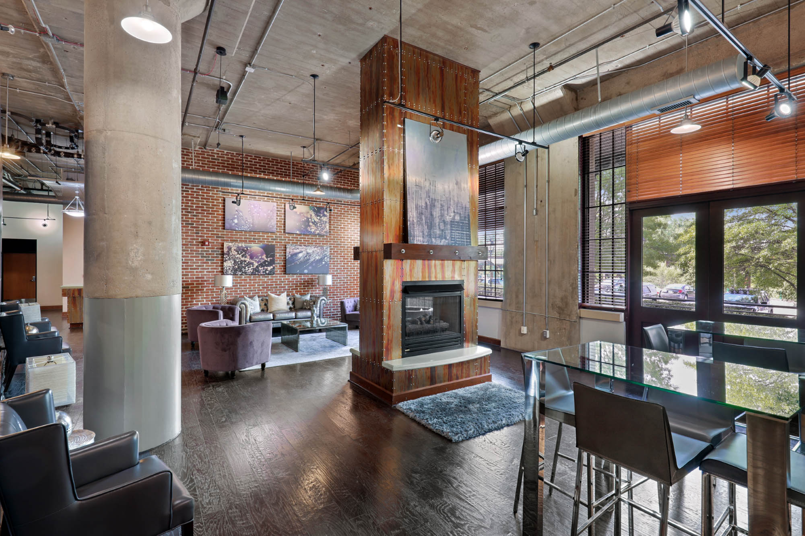 Apartment clubhouse house with a fireplace in the middle of the room at The River Lofts at Tobacco Row offers apartments for rent in Richmond, VA.