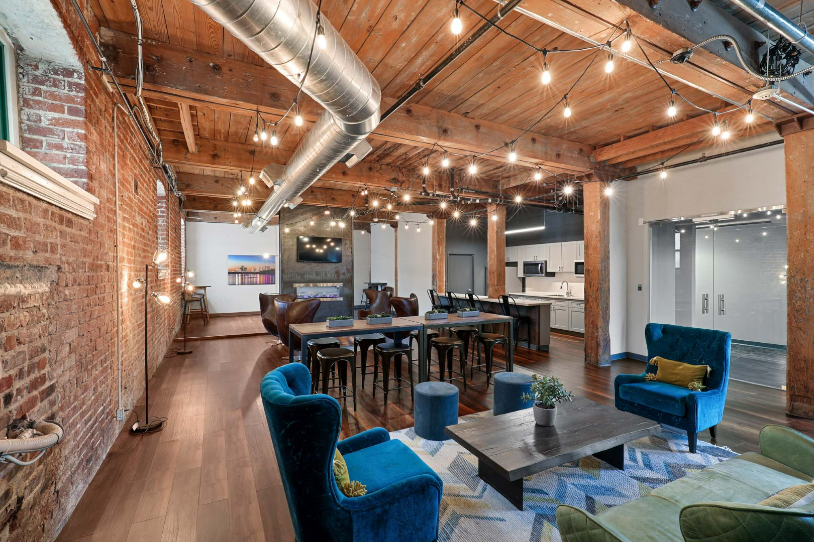 A large clubroom with a lot of furniture and a brick wall at The River Lofts at Tobacco Row offers apartments for rent in Richmond, VA.
