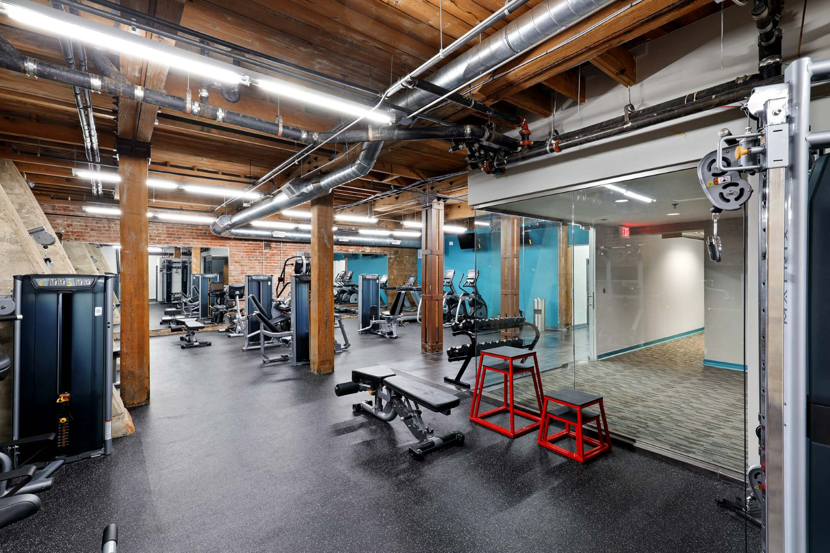 A large gym with a lot of equipment and a mirror at The River Lofts at Tobacco Row offers apartments for rent in Richmond, VA.
