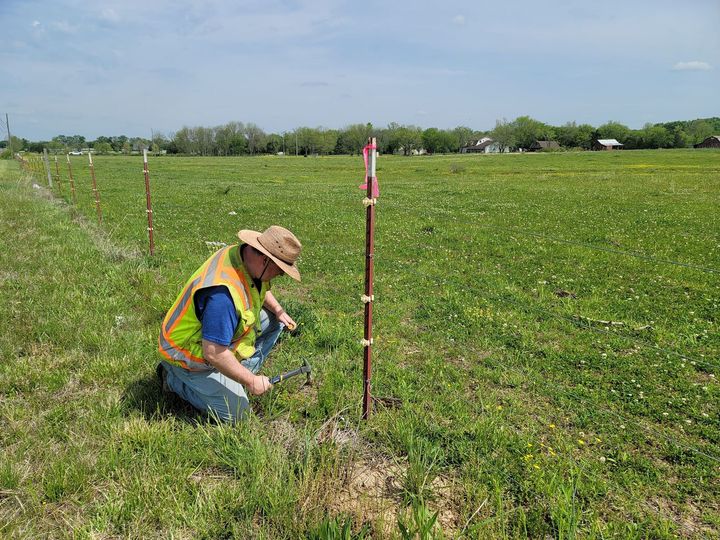 a man is kneeling in the grass in a field