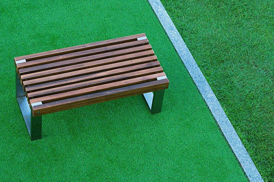 modern bench on turf next to a field made of artificial grass